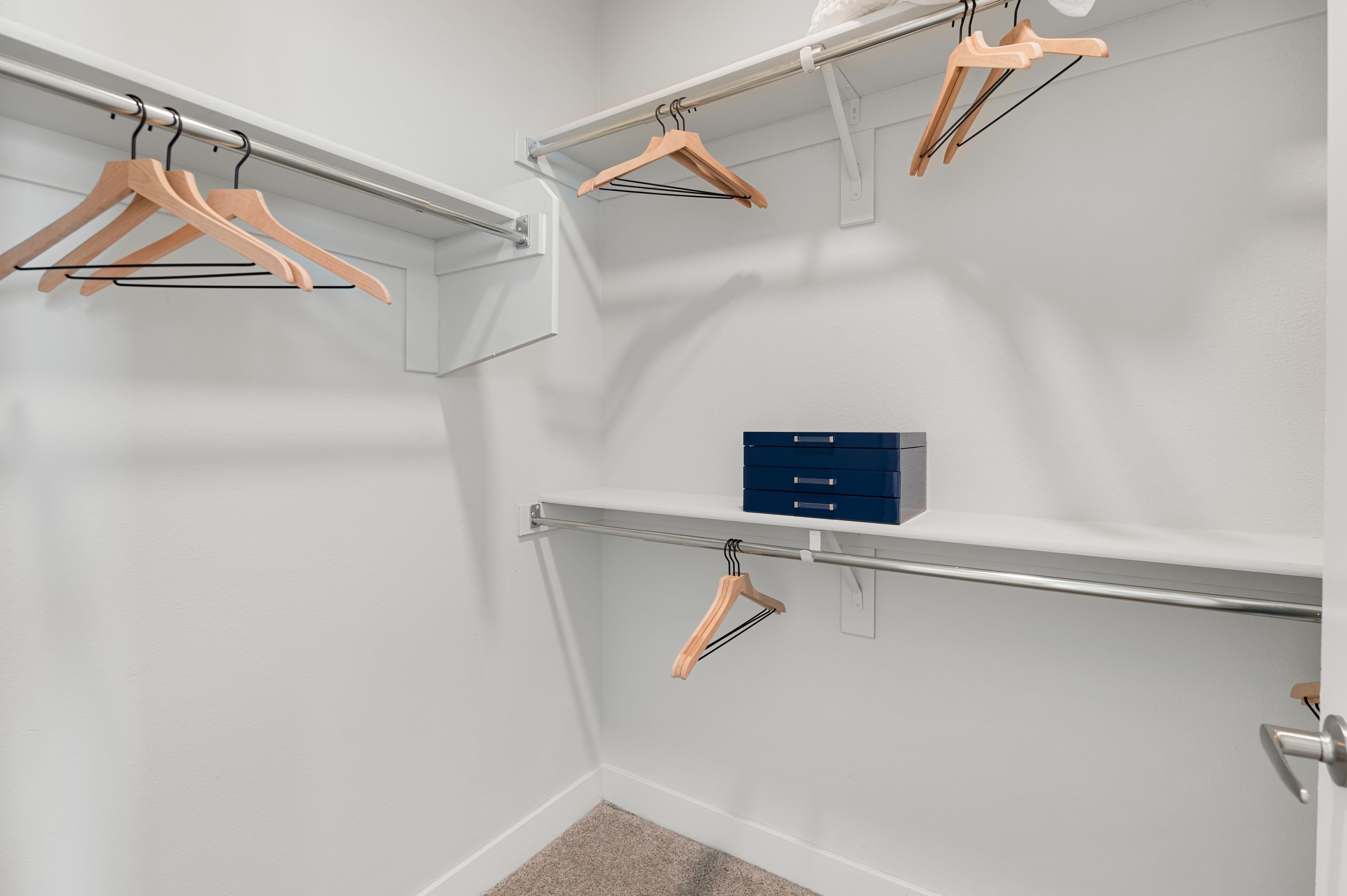 A white closet with a shelf and hangers.