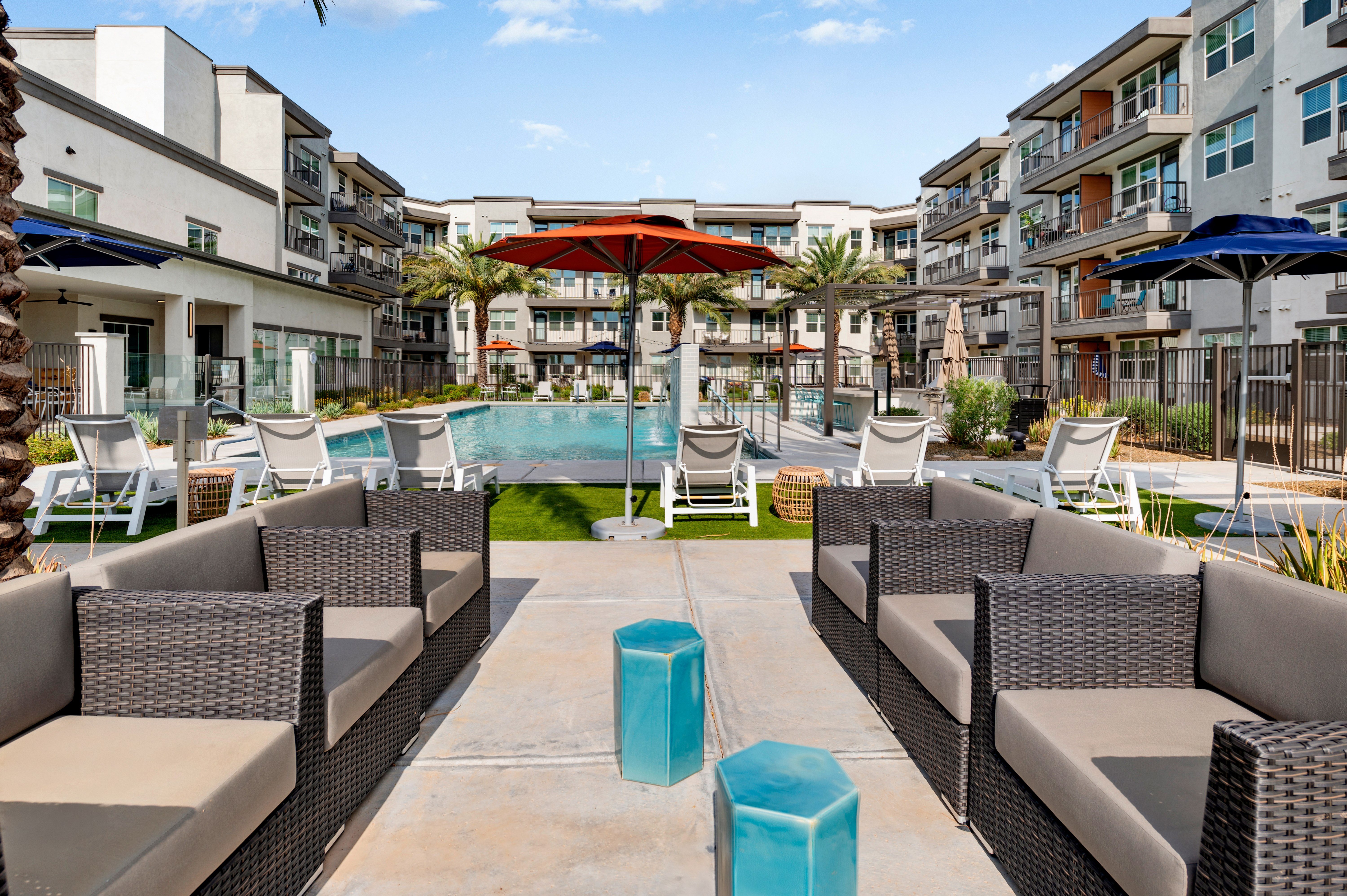 A pool surrounded by lounge chairs and umbrellas.