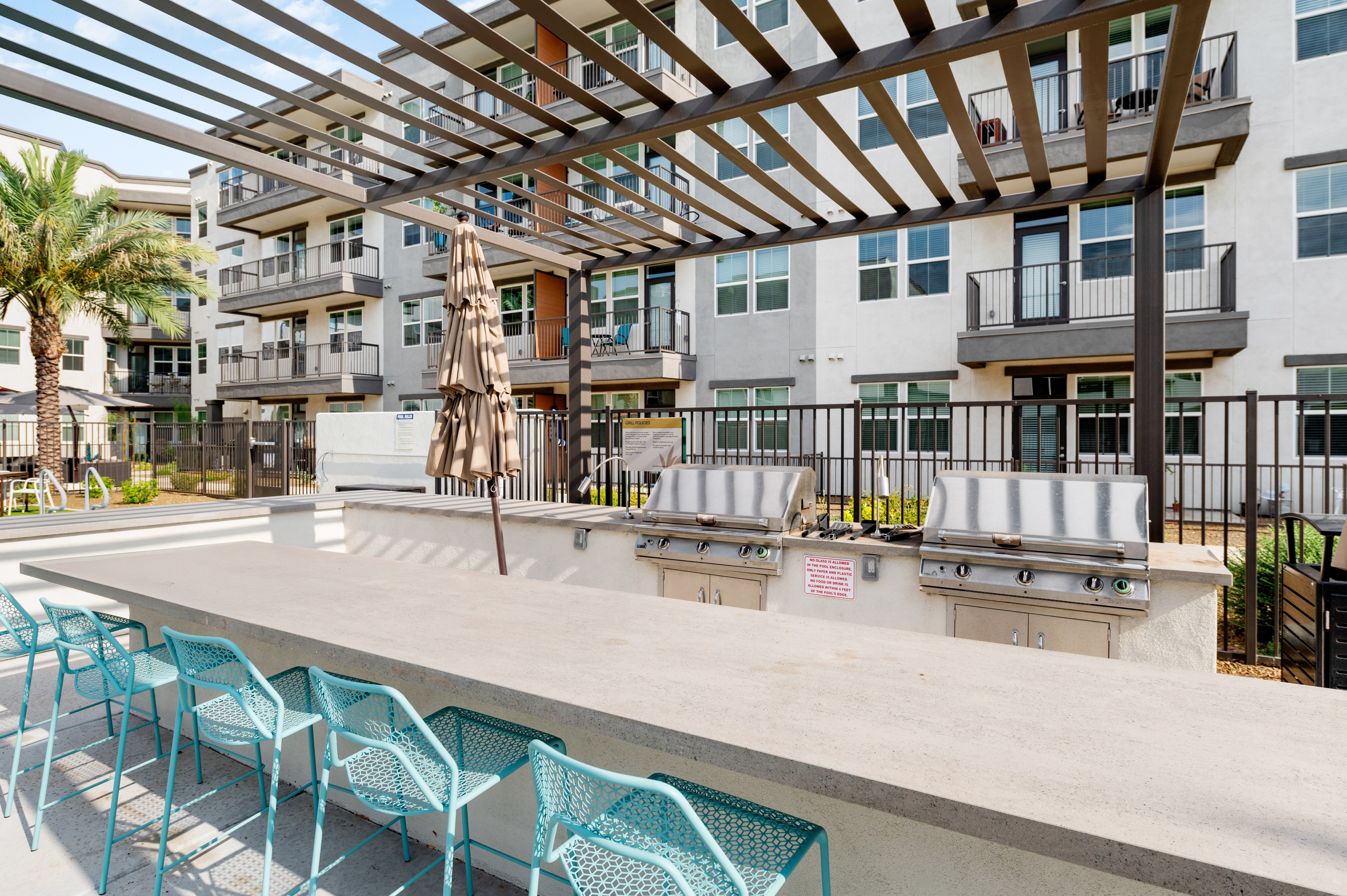 A patio with blue chairs and a table is in front of a building.