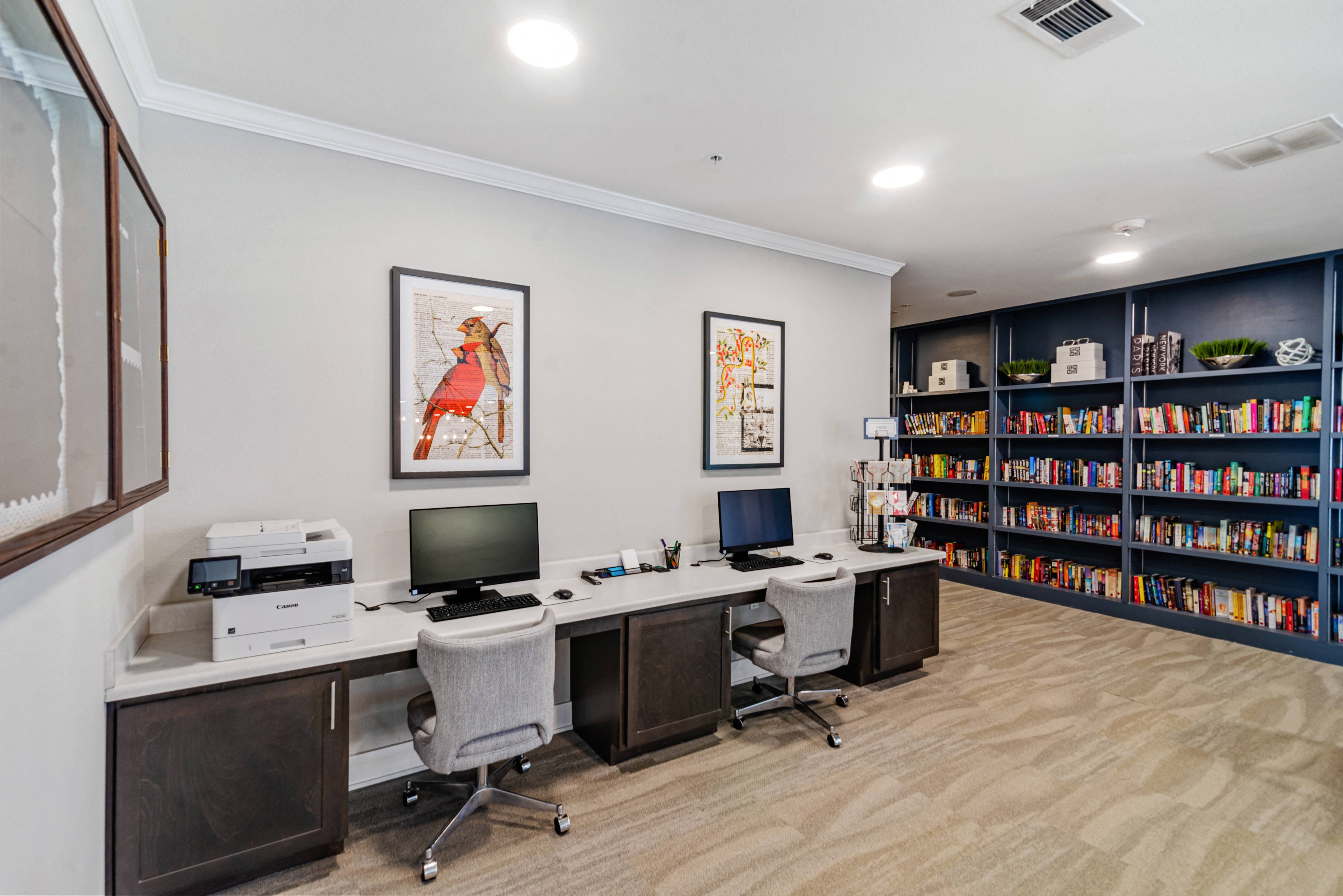 a business center with desktops and a printer in a library at a senior apartment community