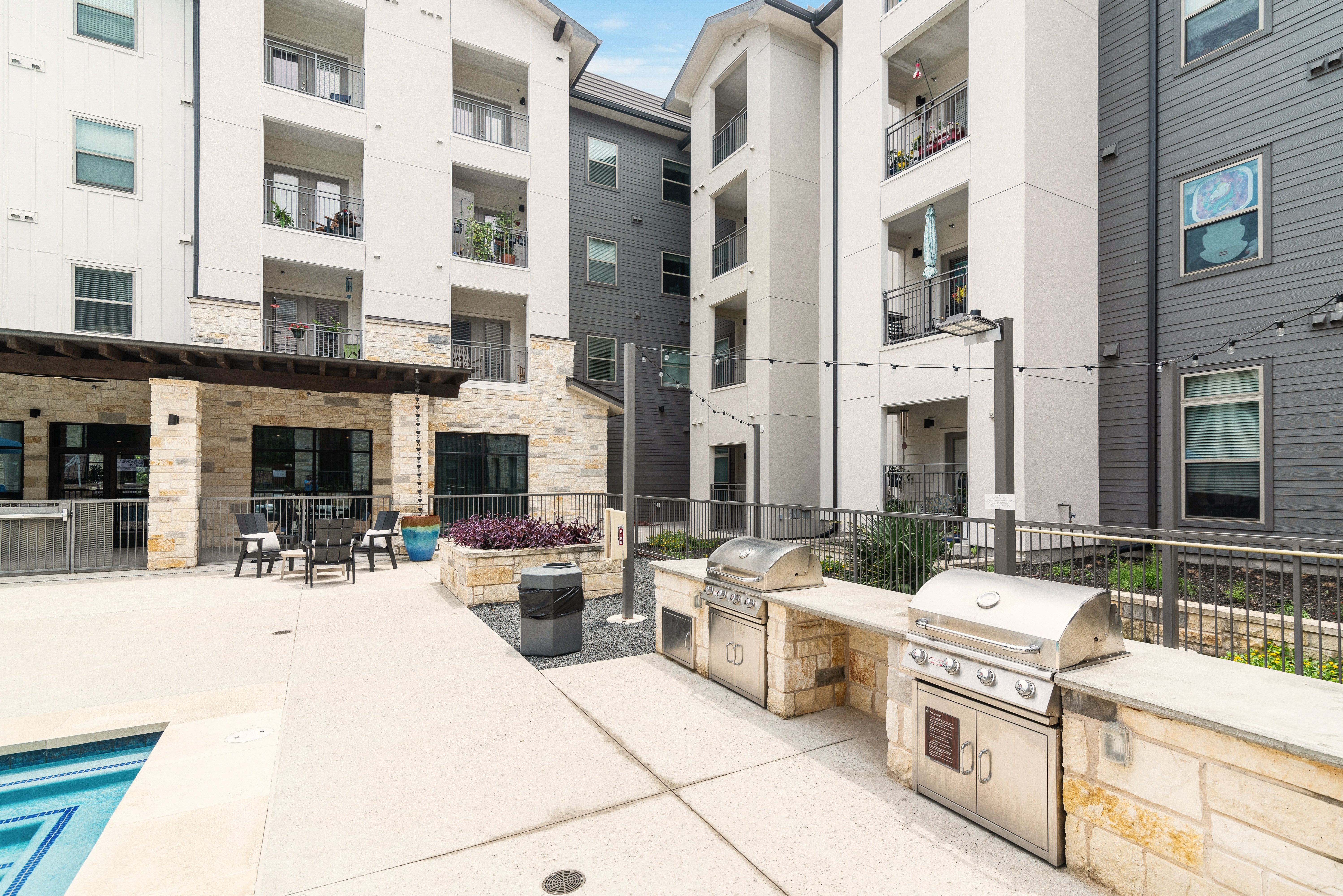 outdoor grilling area next to a pool at a senior apartment community