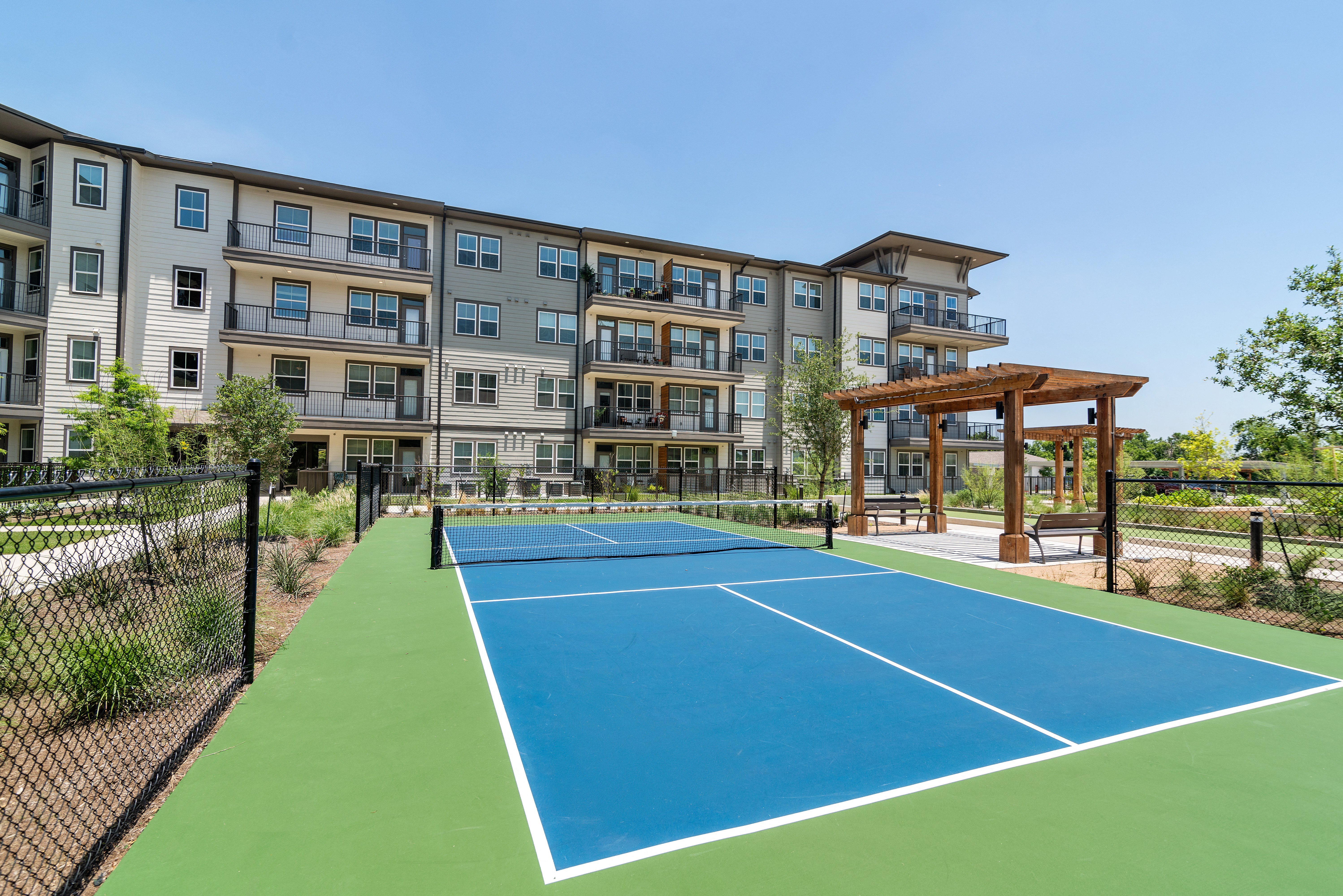 an outdoor tennis court with an apartment building in the background