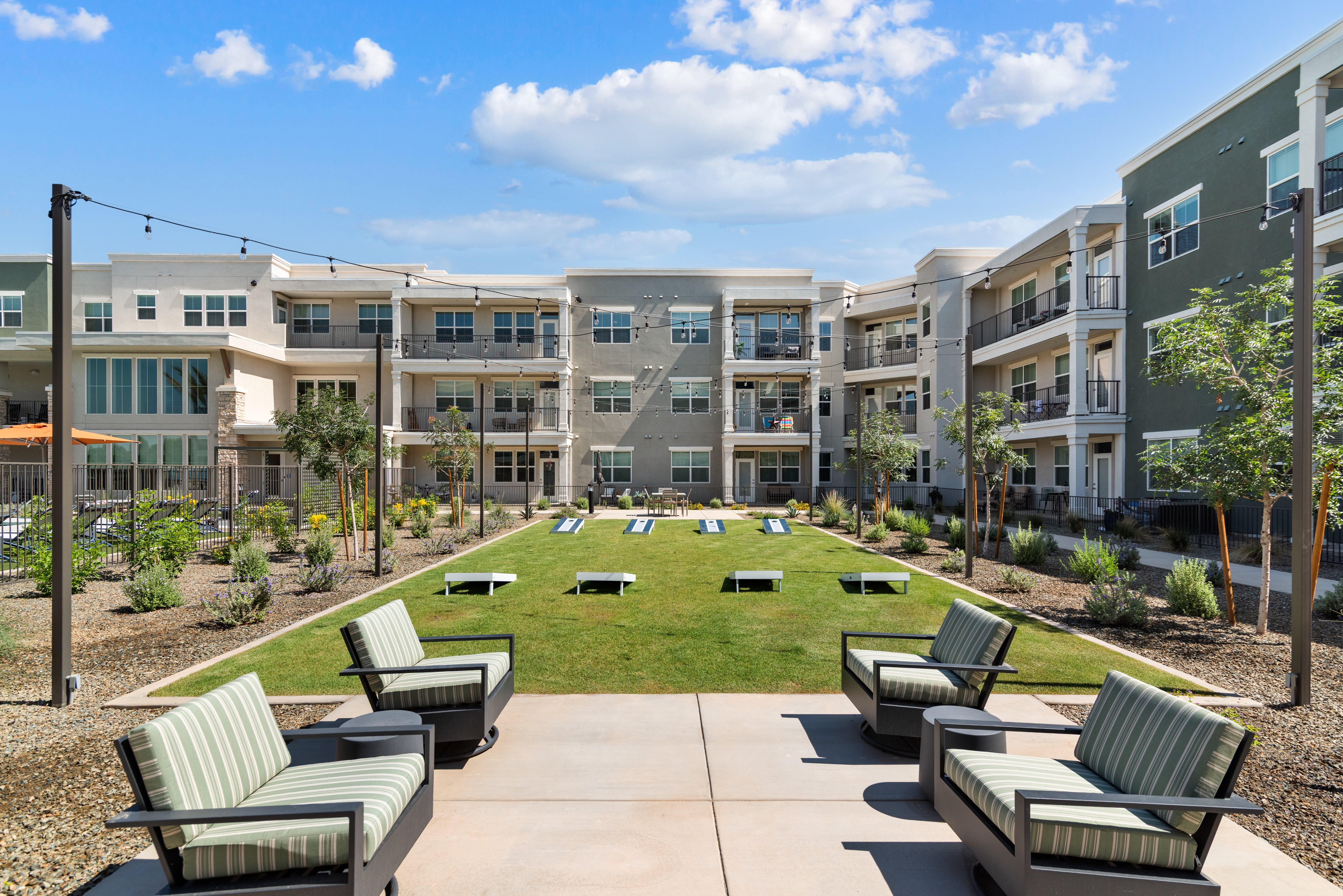 A sunny day at a modern apartment complex with a grassy courtyard and benches.
