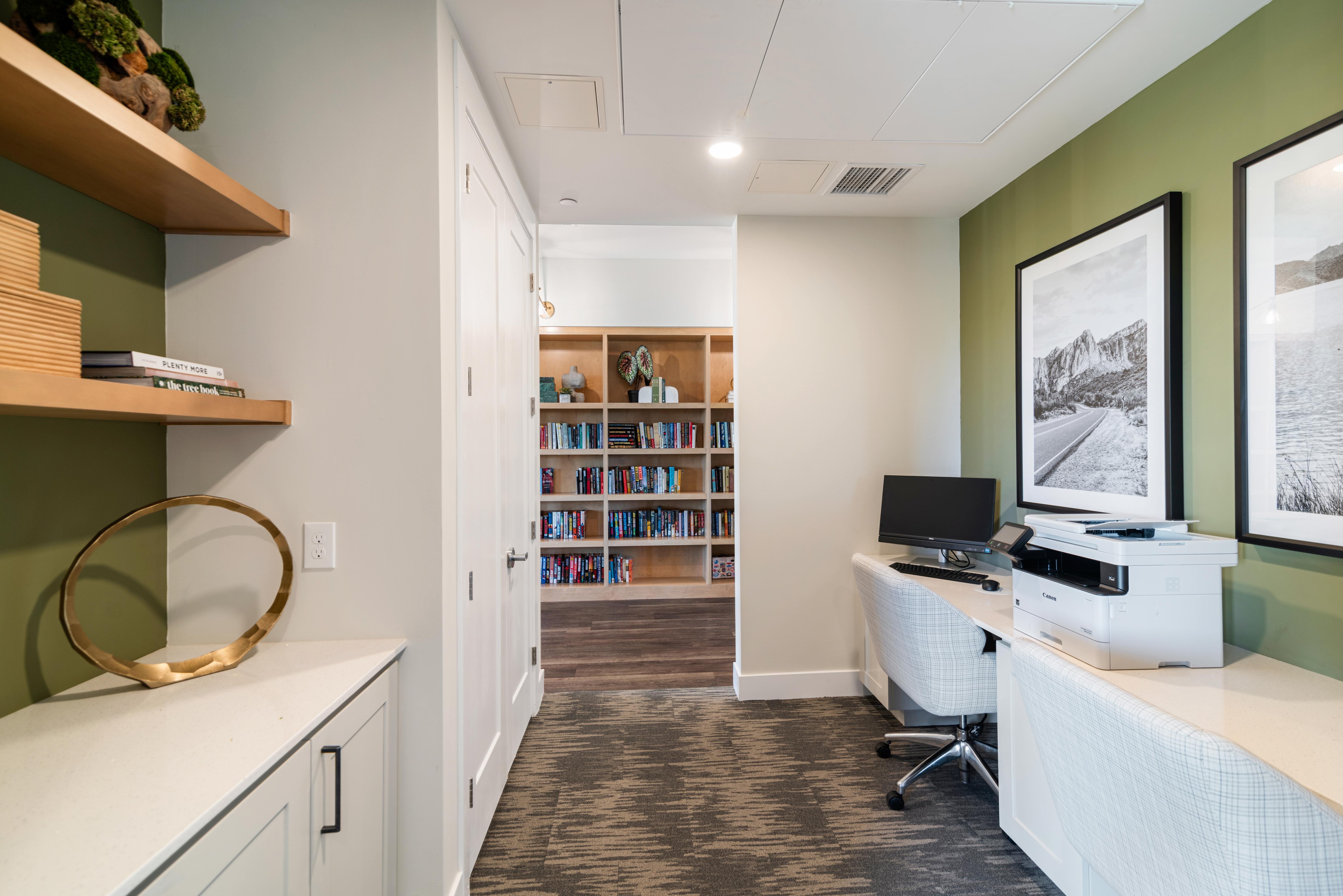 A room with a desk, a chair, a bookshelf, and a framed picture on the wall.