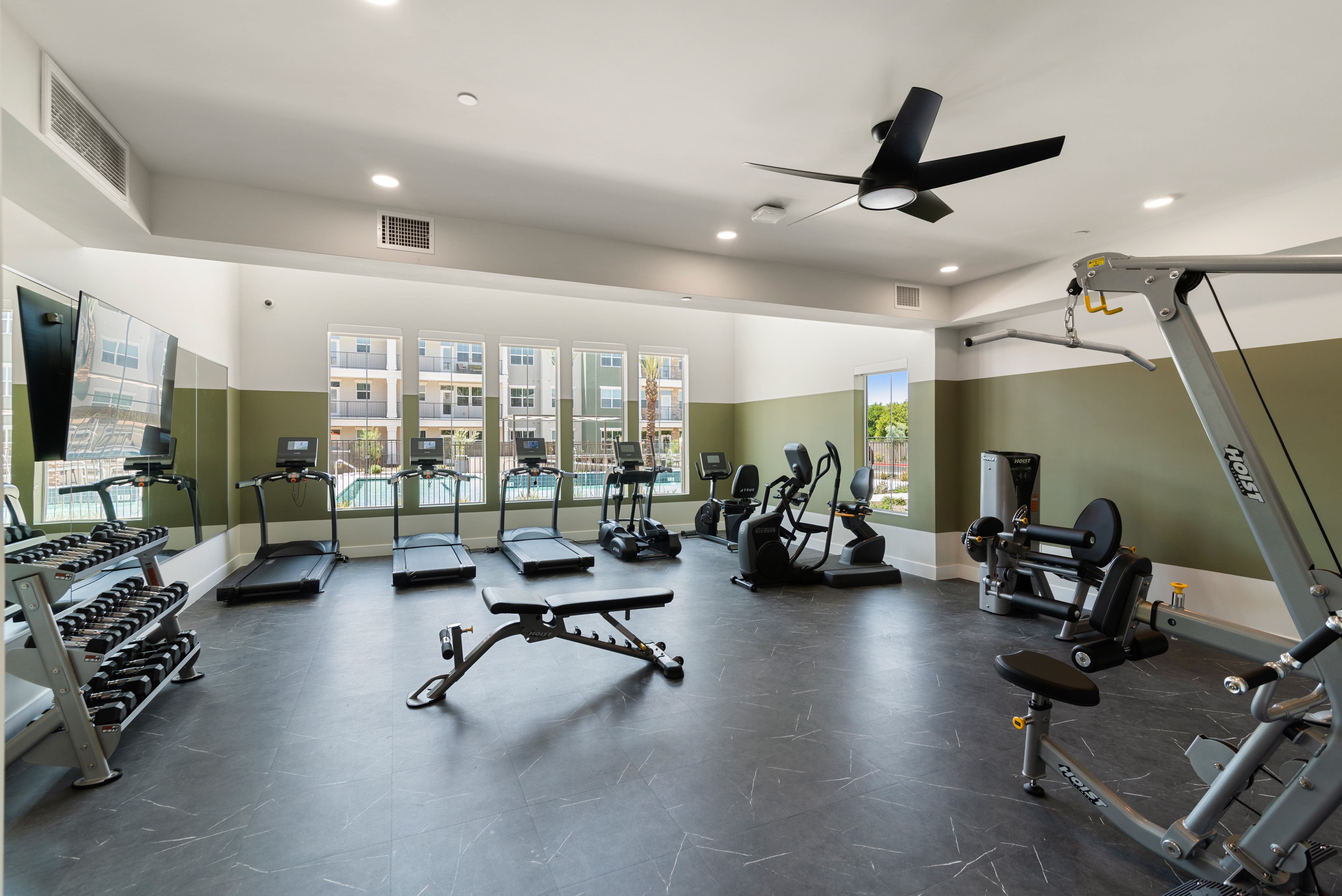 A spacious gym with a variety of equipment including treadmills, weights, and a fan.