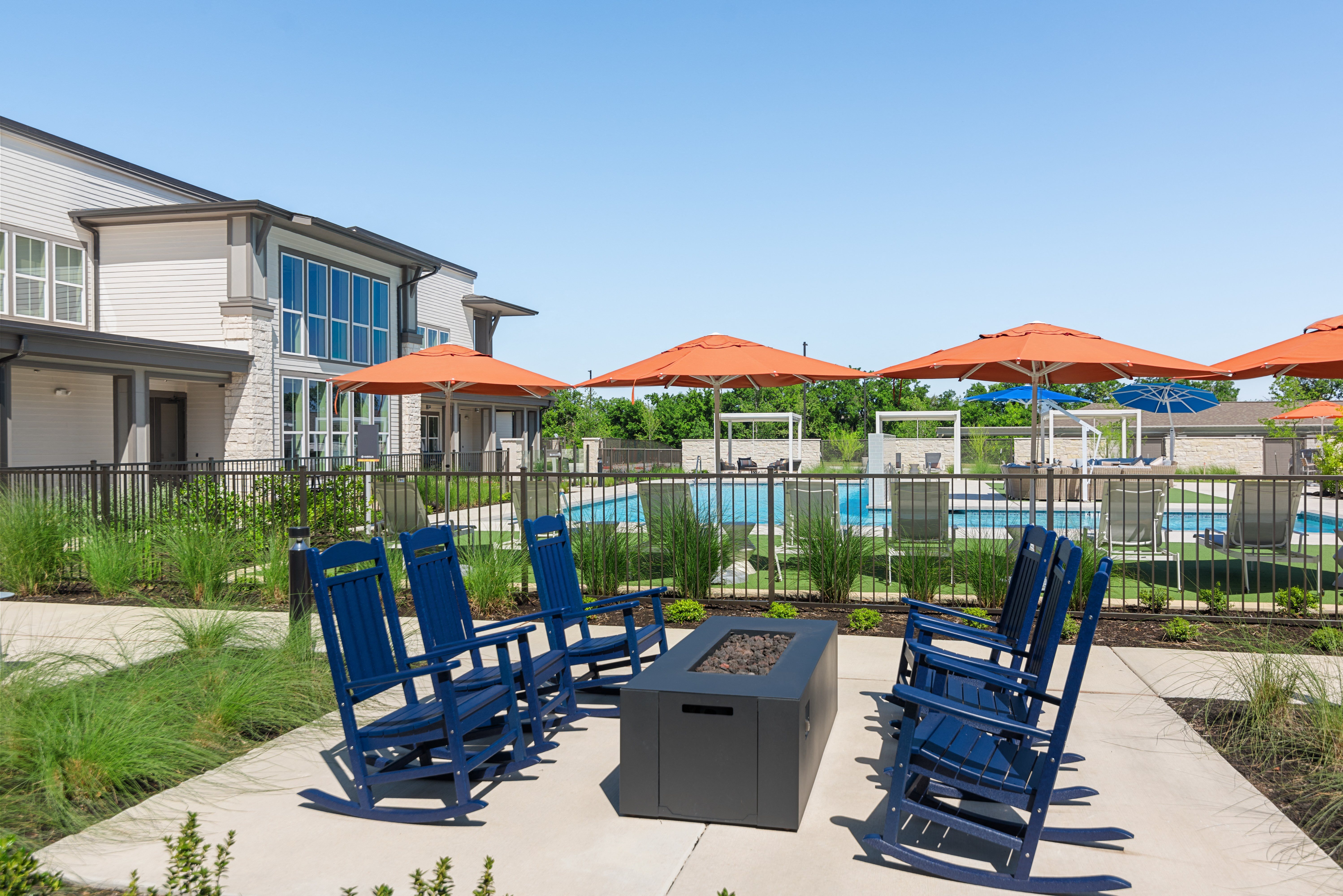 a patio with blue chairs and umbrellas next to a pool