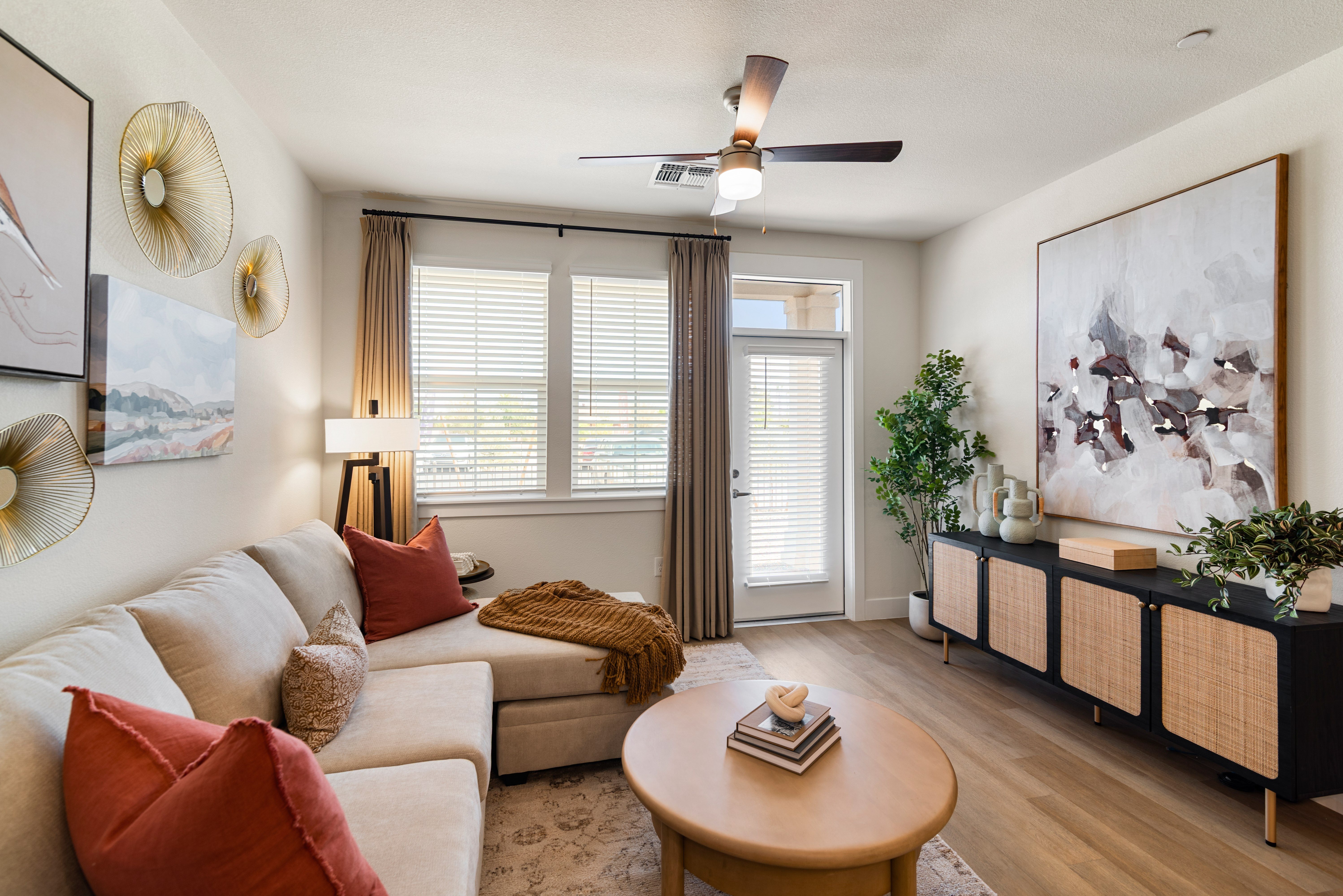 A living room with a beige couch, a brown coffee table, and a large abstract painting on the wall.