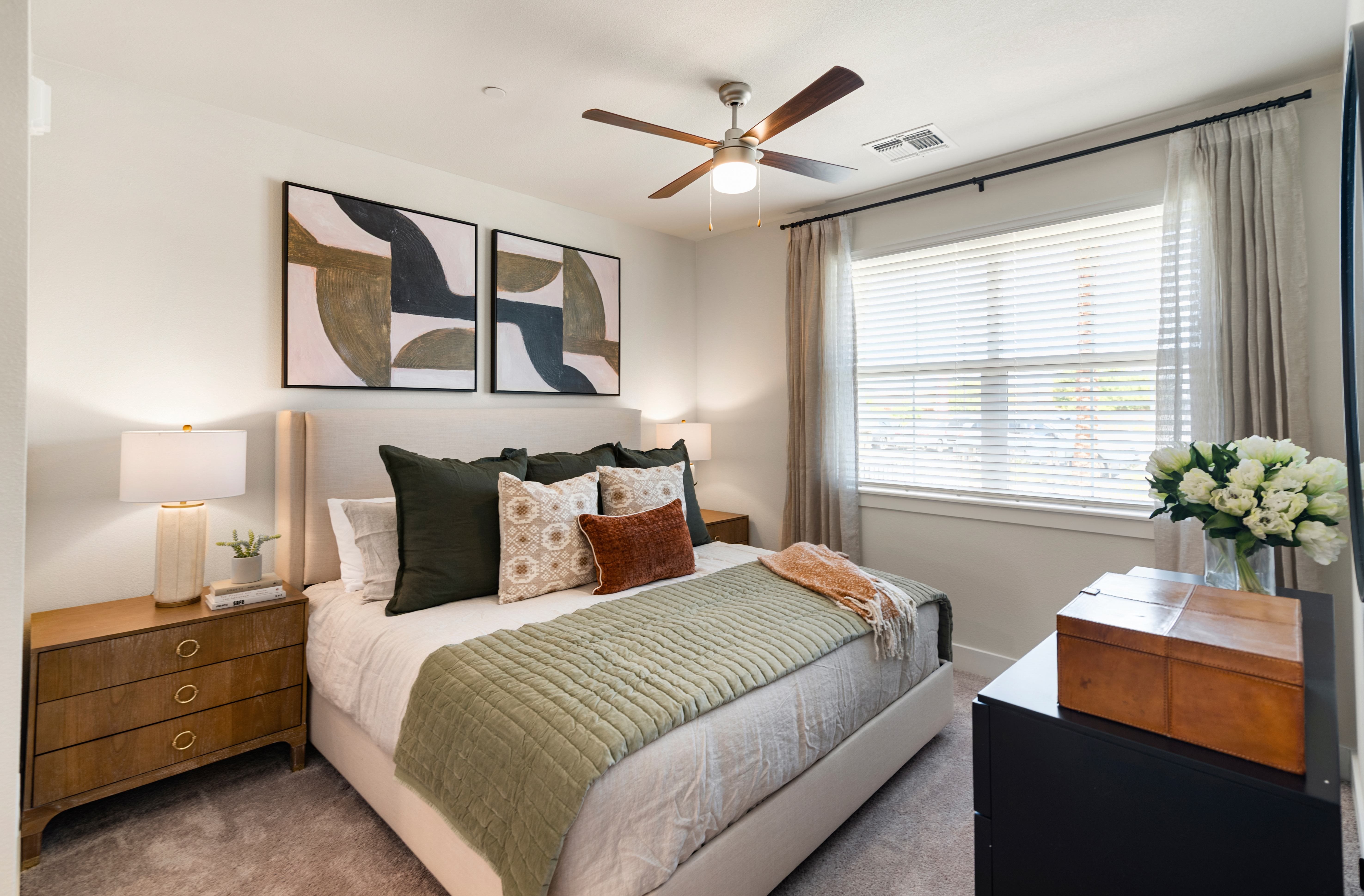 A bedroom with a bed, nightstand, and a ceiling fan.