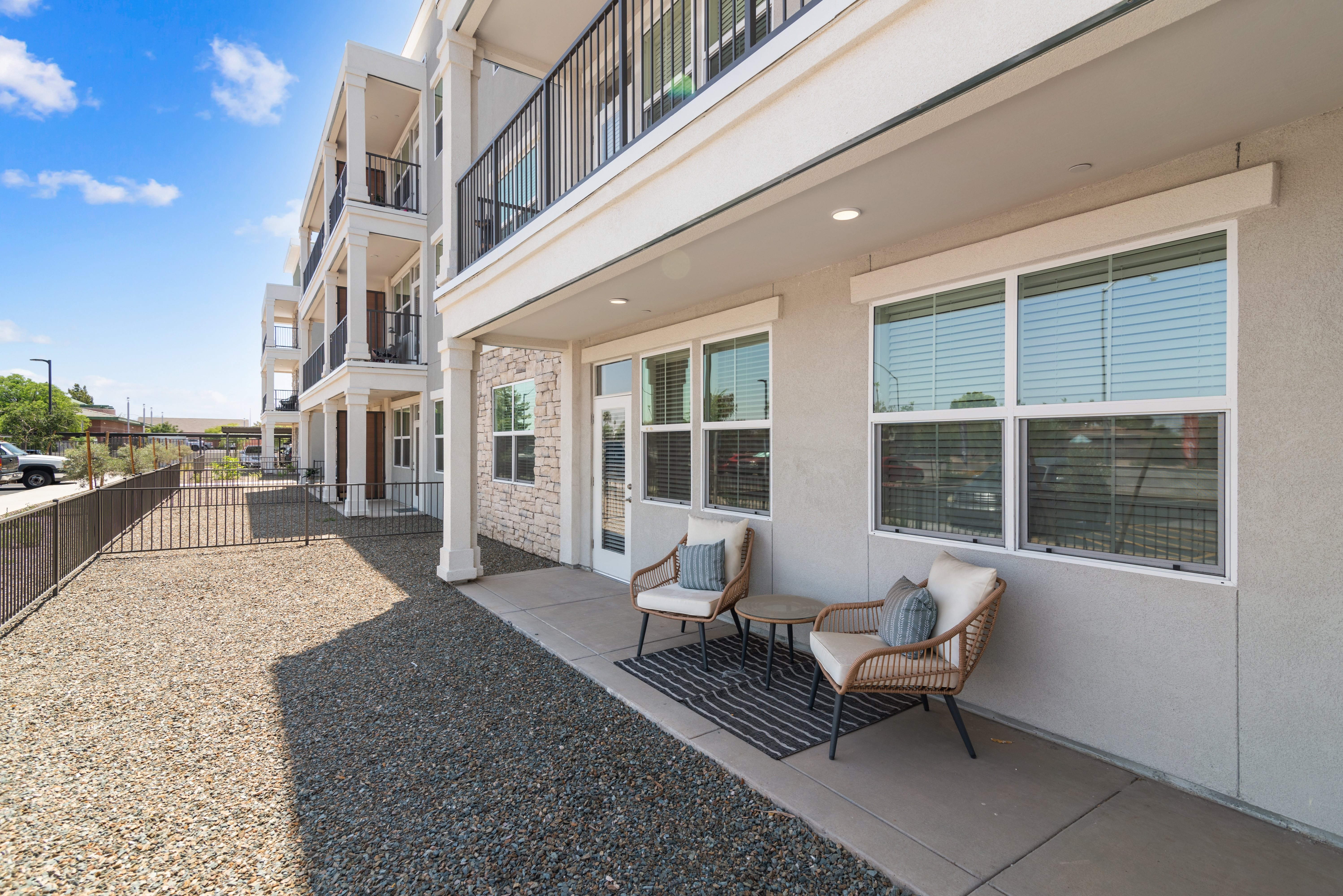 A modern apartment building with a gravel courtyard and outdoor furniture.