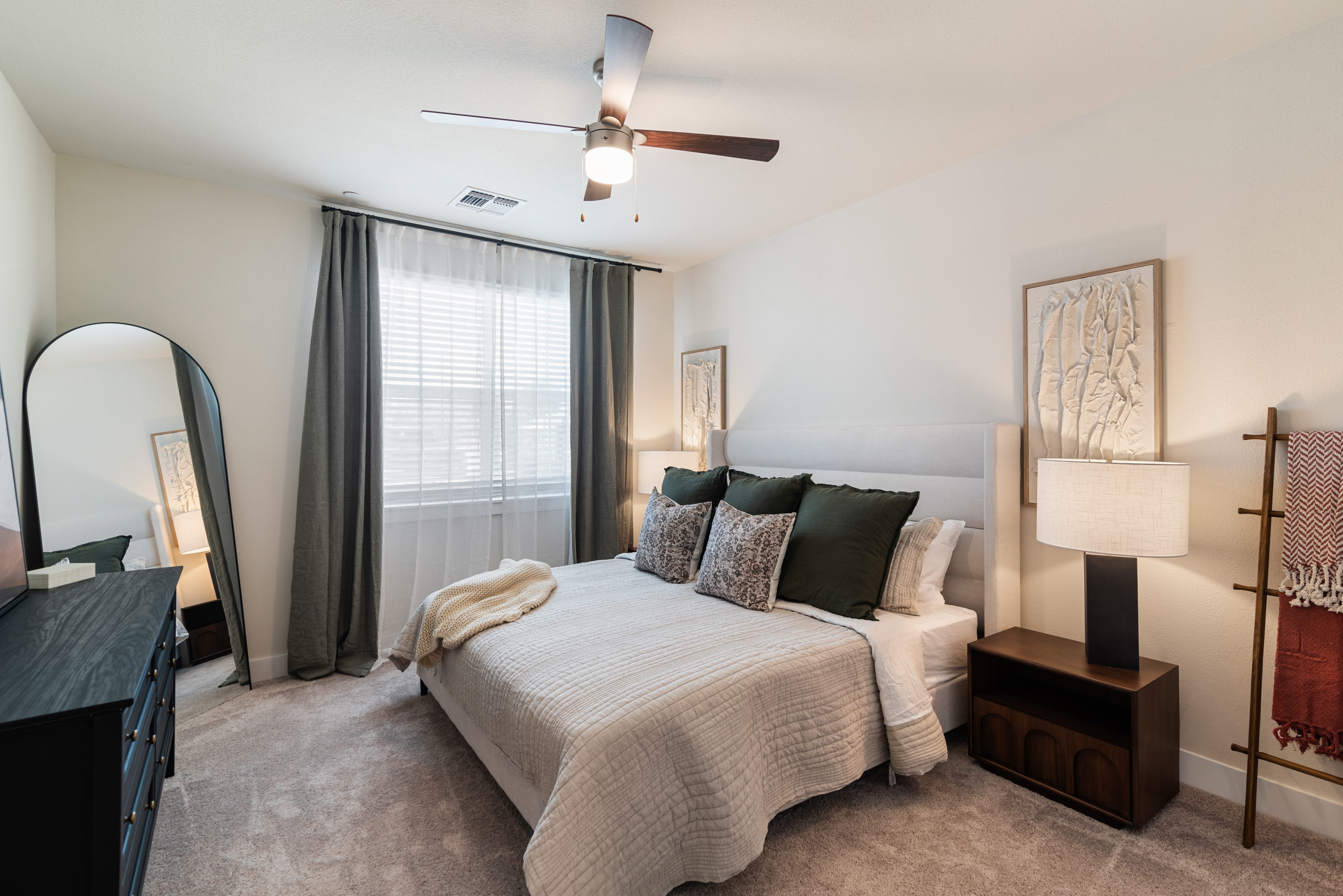 A bedroom with a bed, nightstand, and a ceiling fan.