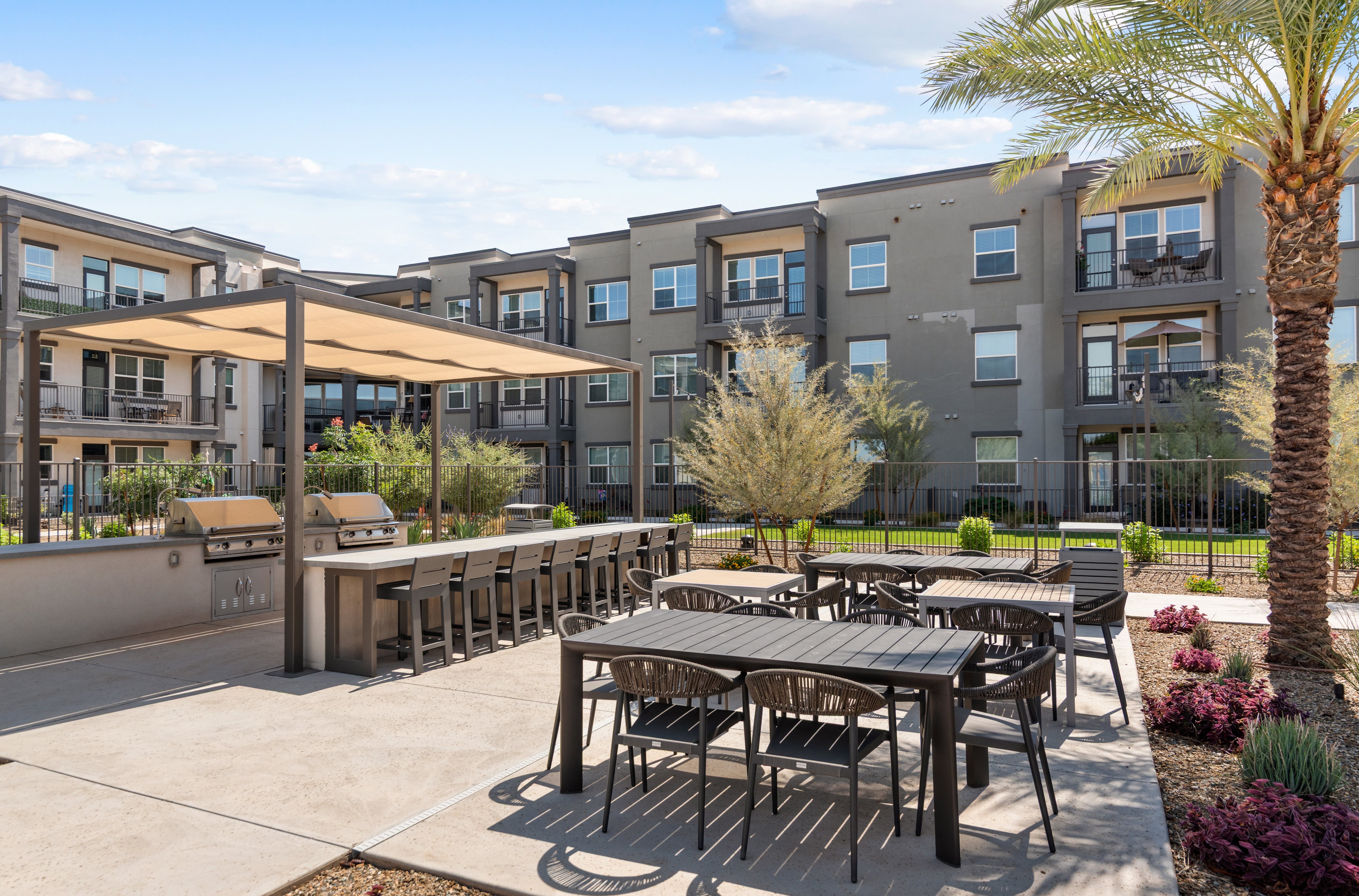 A patio with tables and chairs is surrounded by apartment buildings.