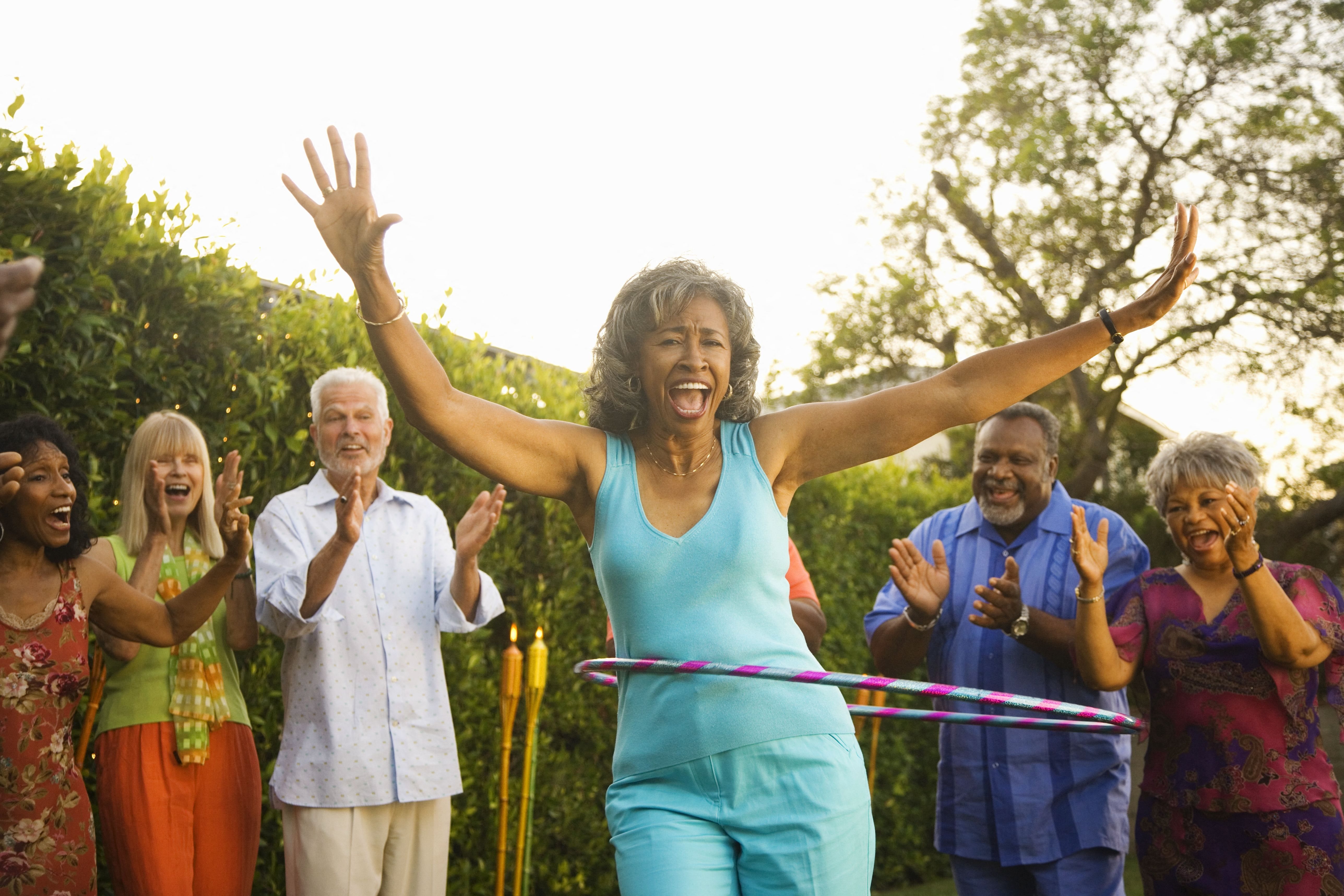a group of people playing with hula hoops outside at a senior apartment community