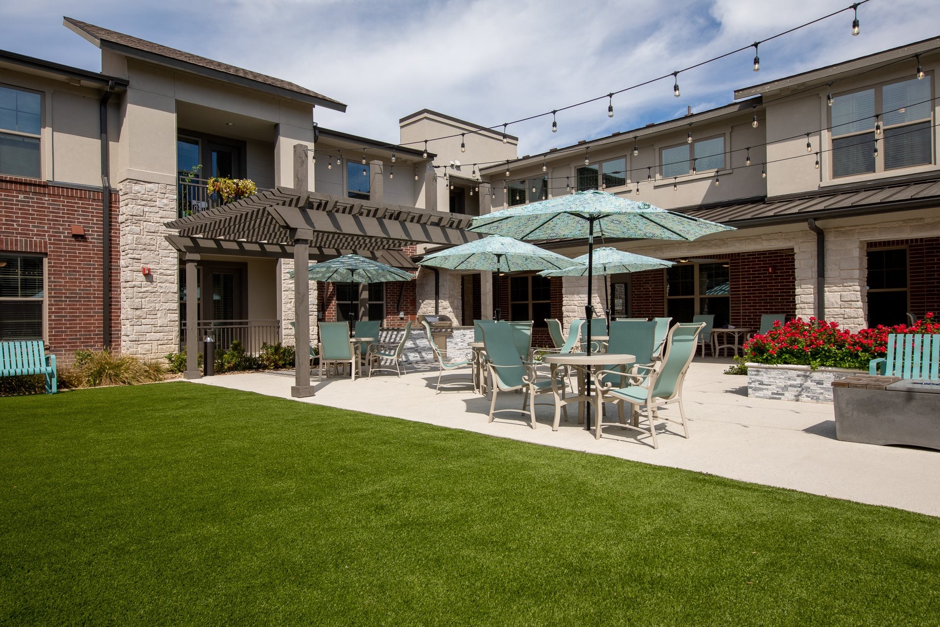 a patio with tables and chairs under an umbrella at a senior apartment community