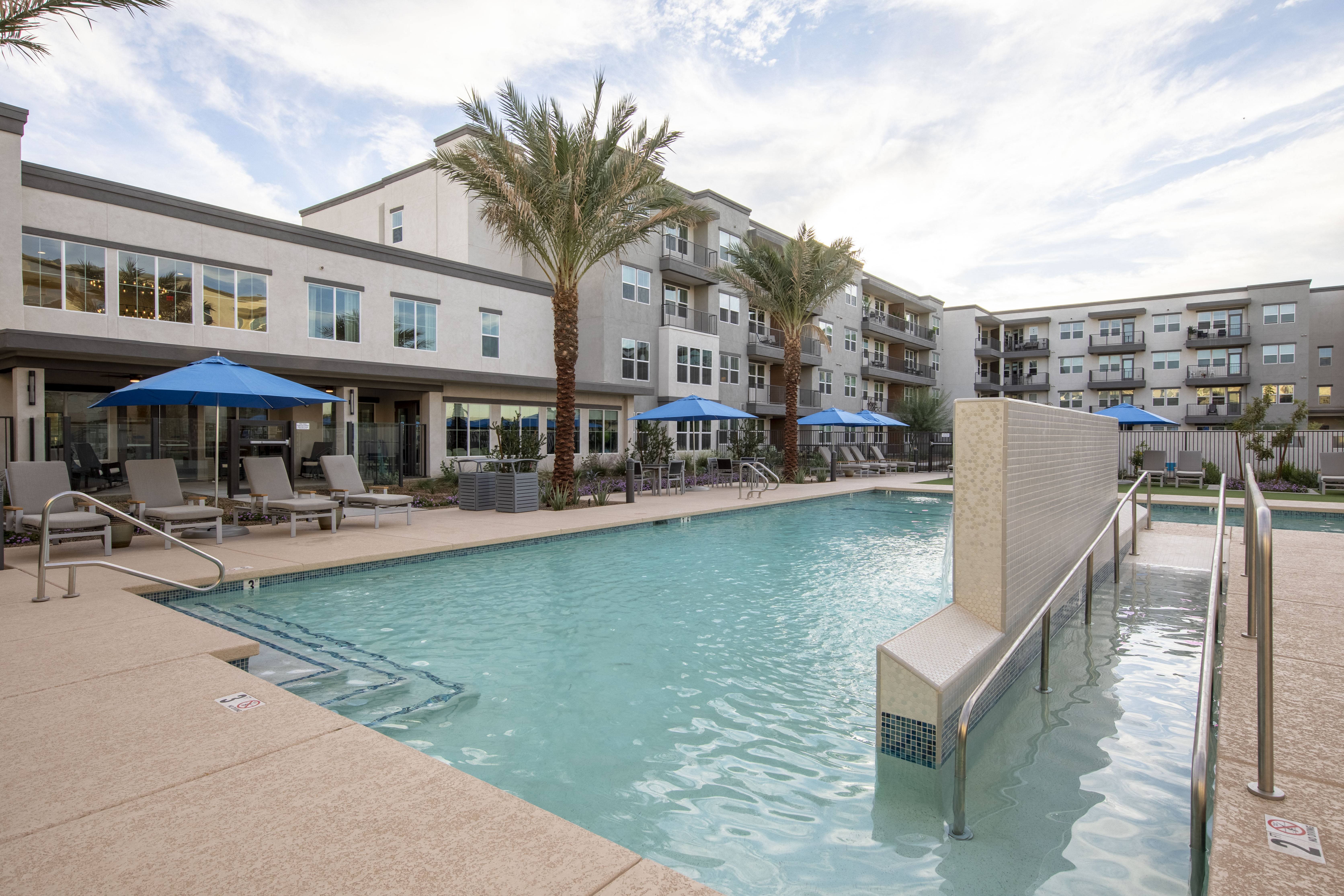 a resort-style pool with covered sitting areas at a senior apartment community