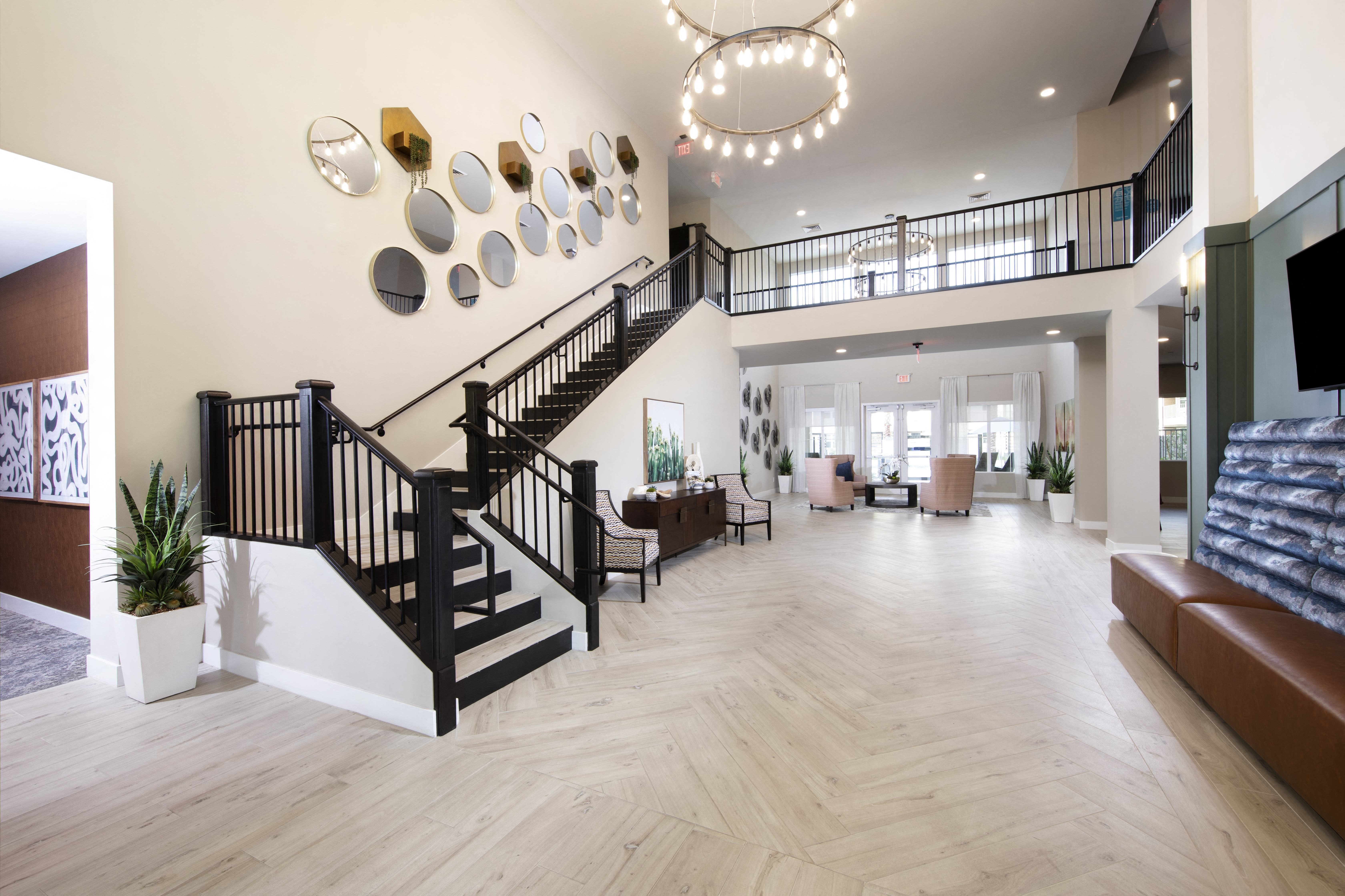 a large living room with a staircase and a lobby lounge area at a senior apartment community