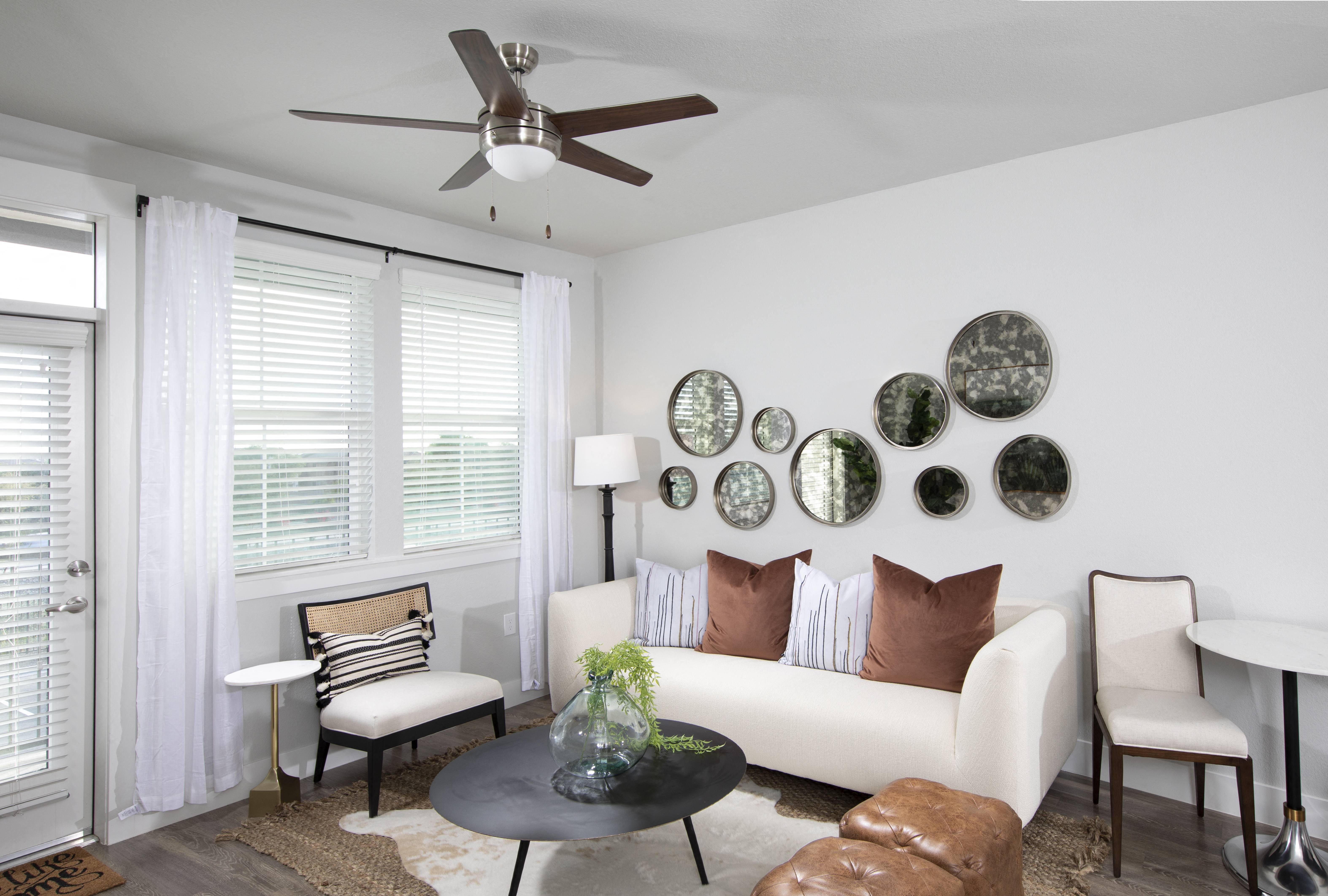 a living room with a ceiling fan and windows at a senior apartment community