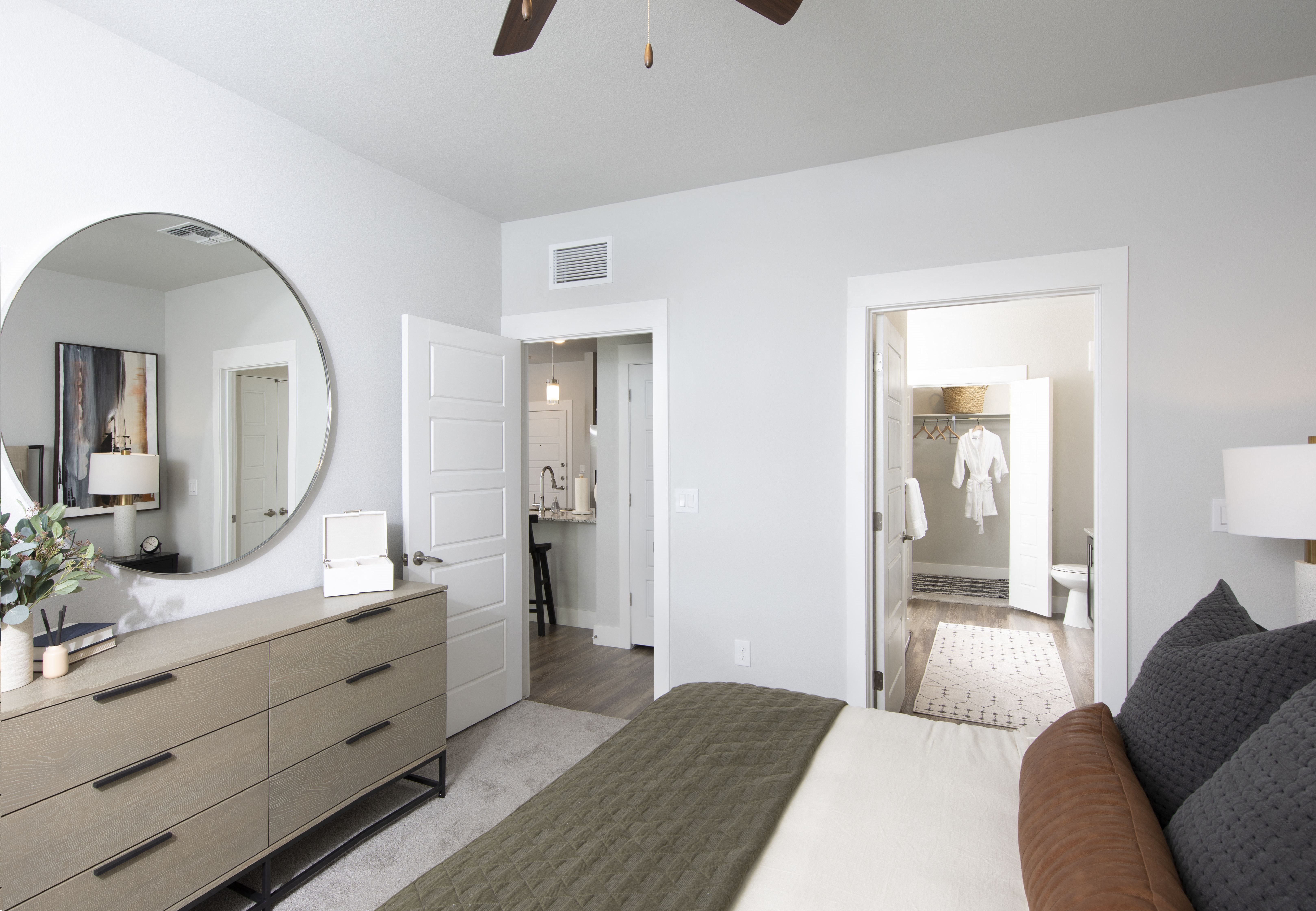 a bedroom with a queen-sized bed, dresser, and closet entrance at a senior apartment community