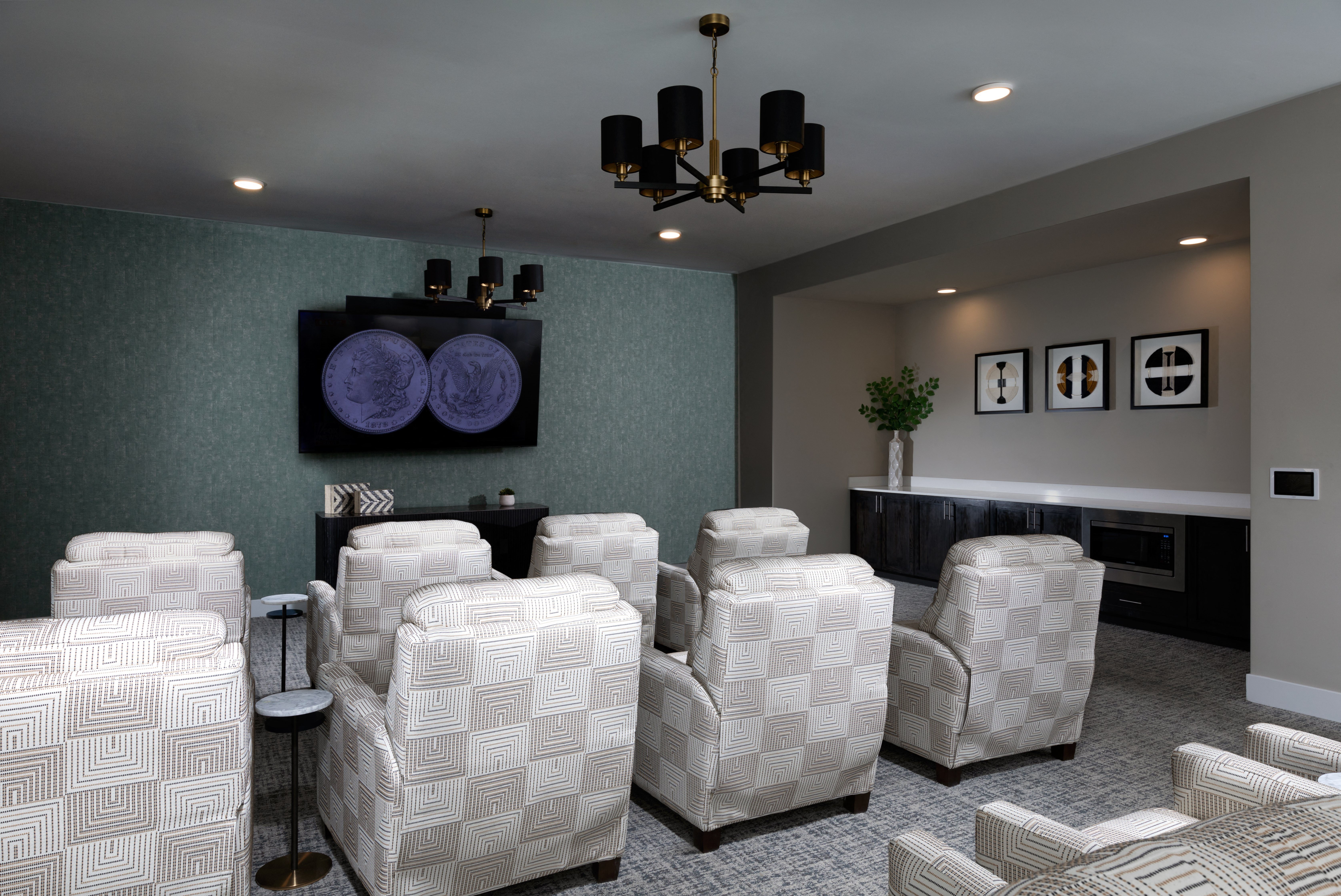 a media room with comfortable chairs and a screen at a senior apartment community