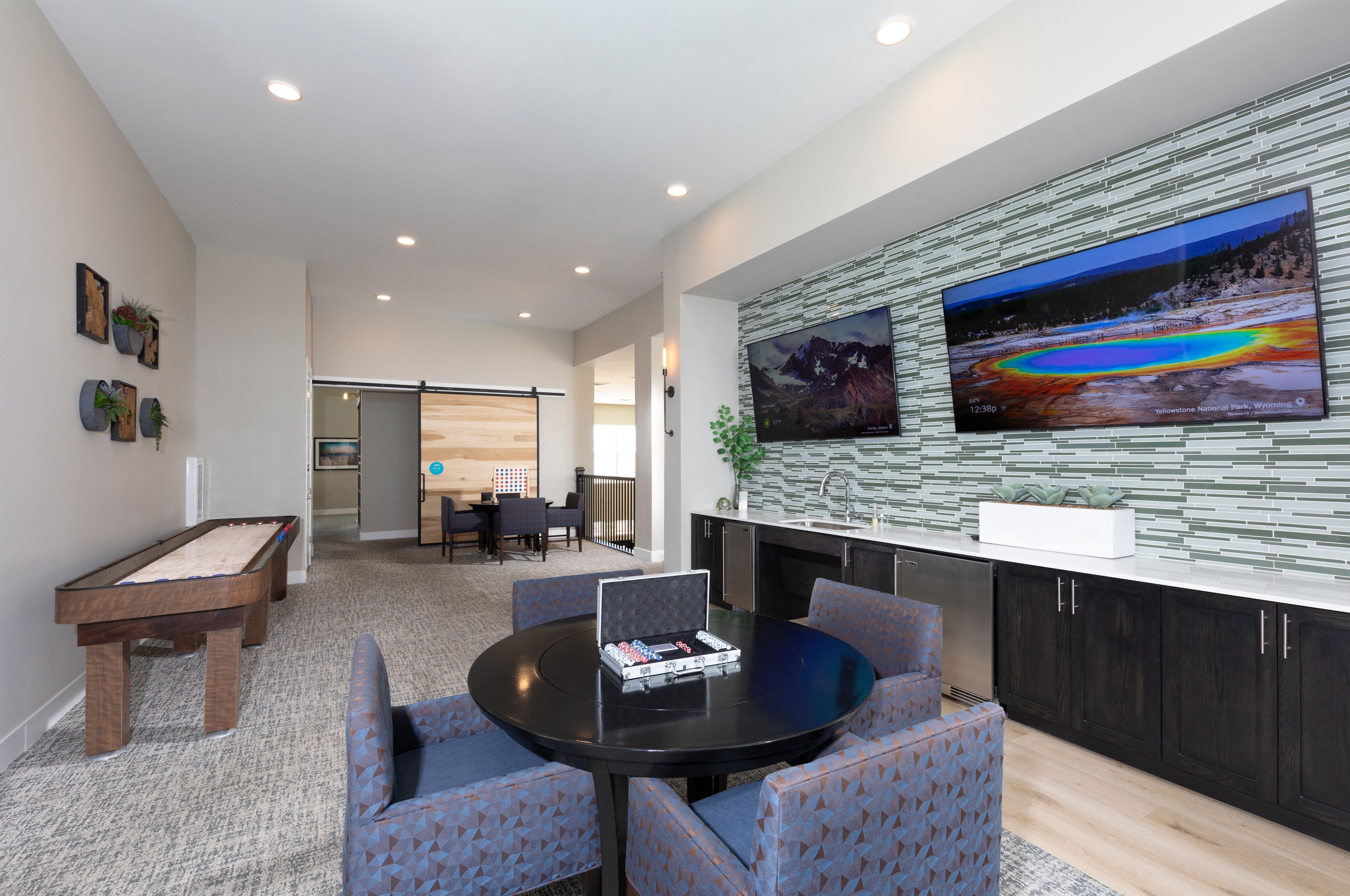 a game room with sitting areas and televisions at a senior apartment community