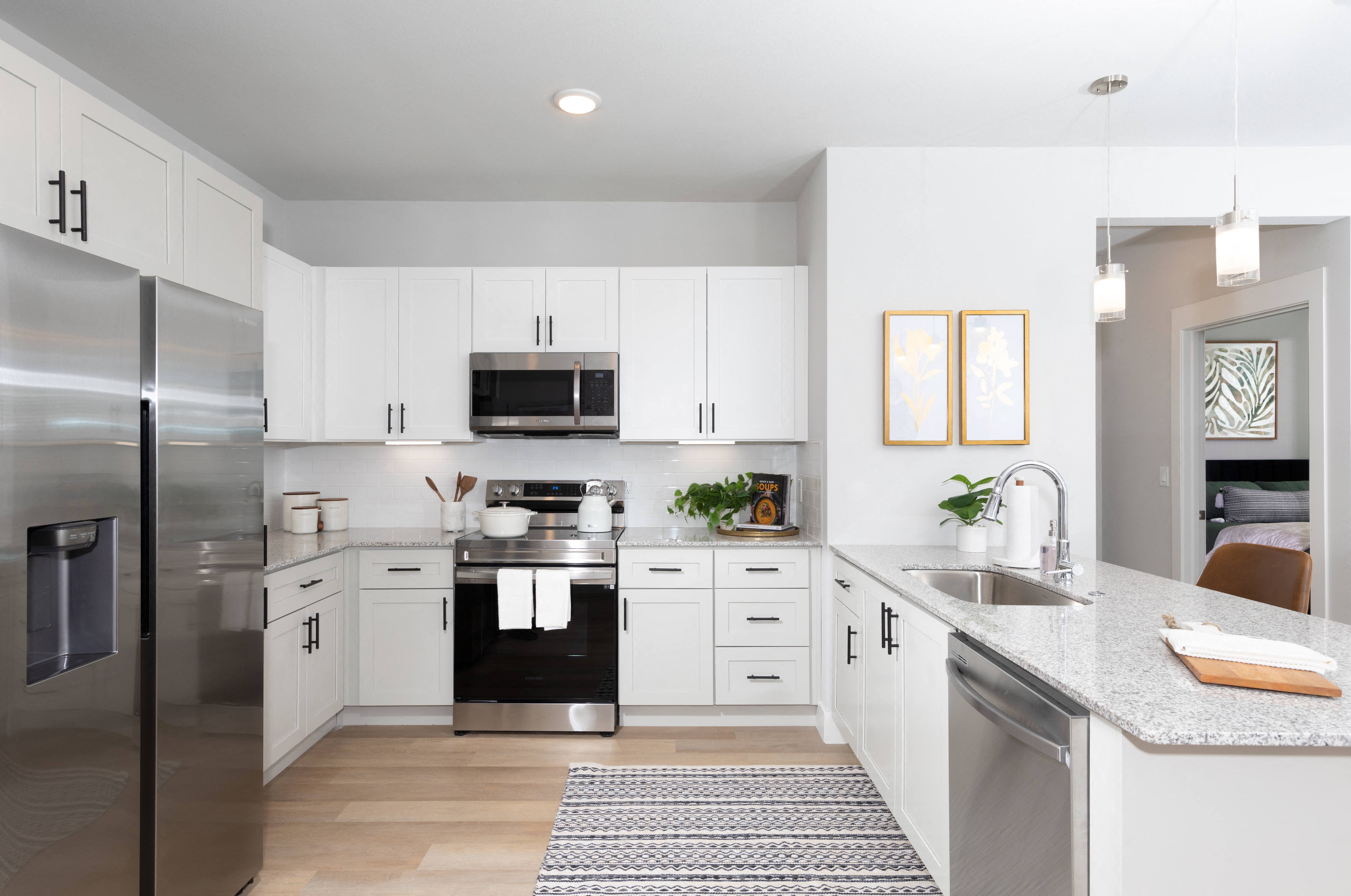 a kitchen with stainless steel appliances and granite countertops at a senior apartment community