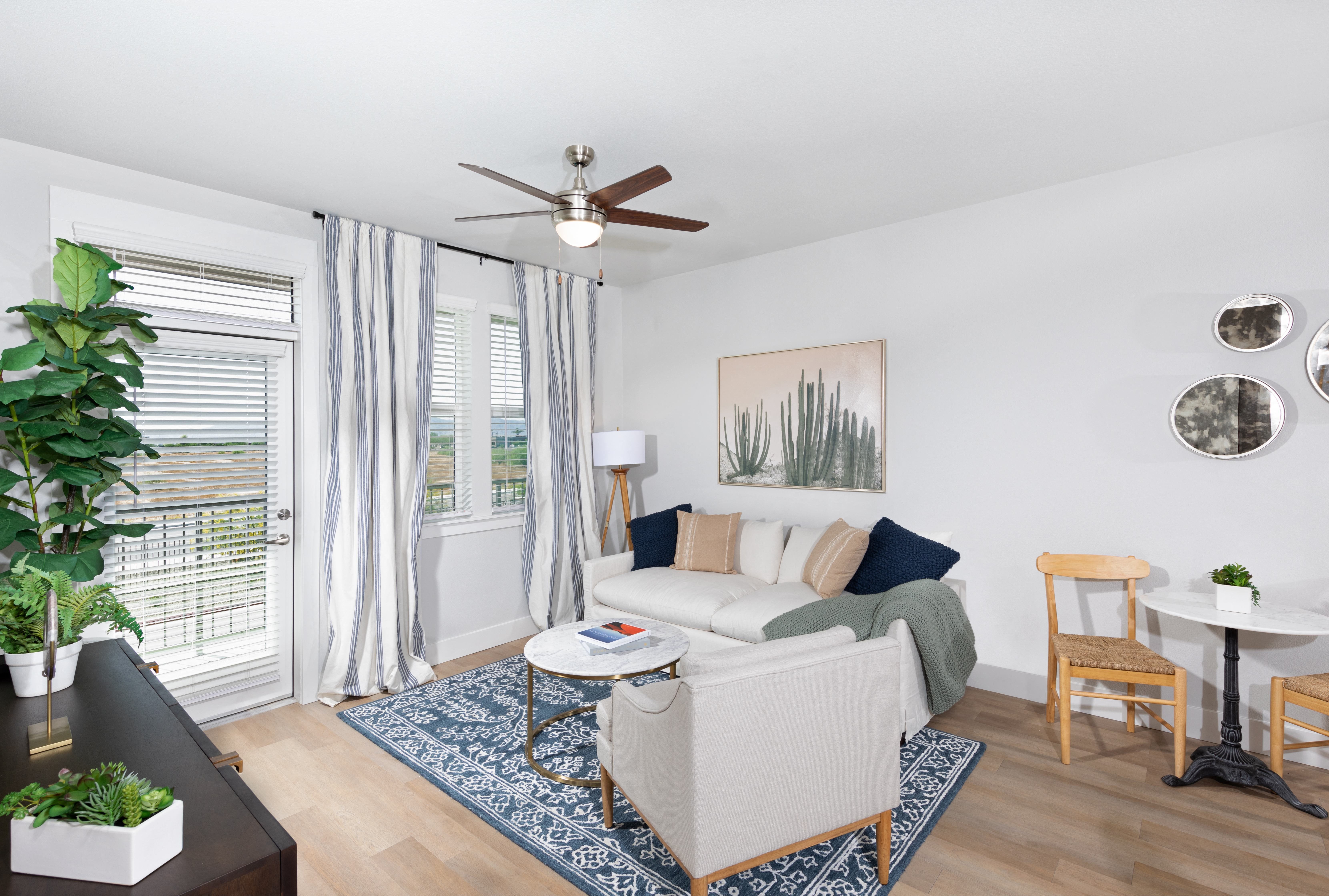 a living room with a ceiling fan and door leading to a patio at a senior apartment community