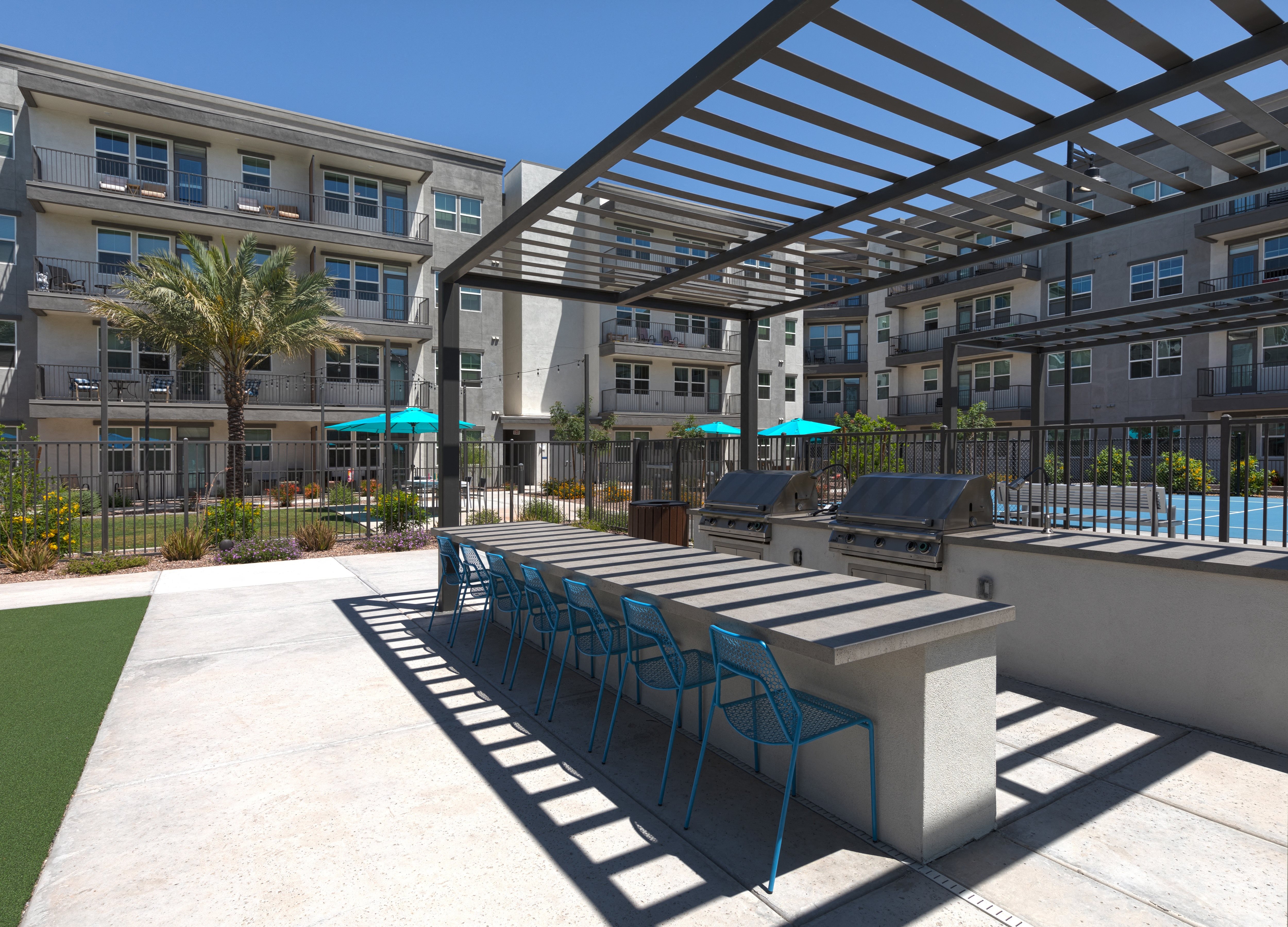 a covered, outdoor grilling station with a large island and chairs at a senior apartment community
