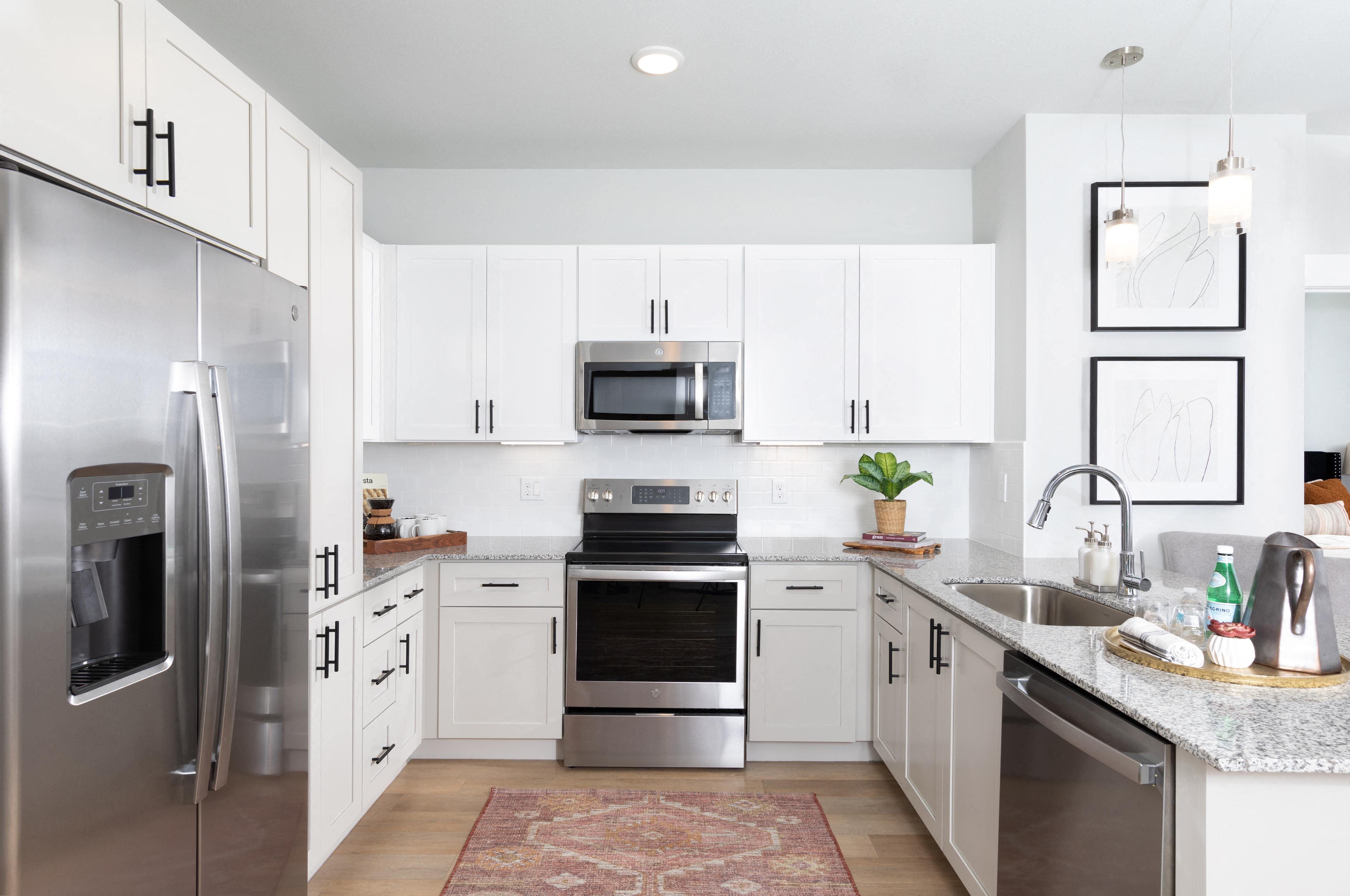 a kitchen with stainless steel appliances and granite countertops at a senior apartment community