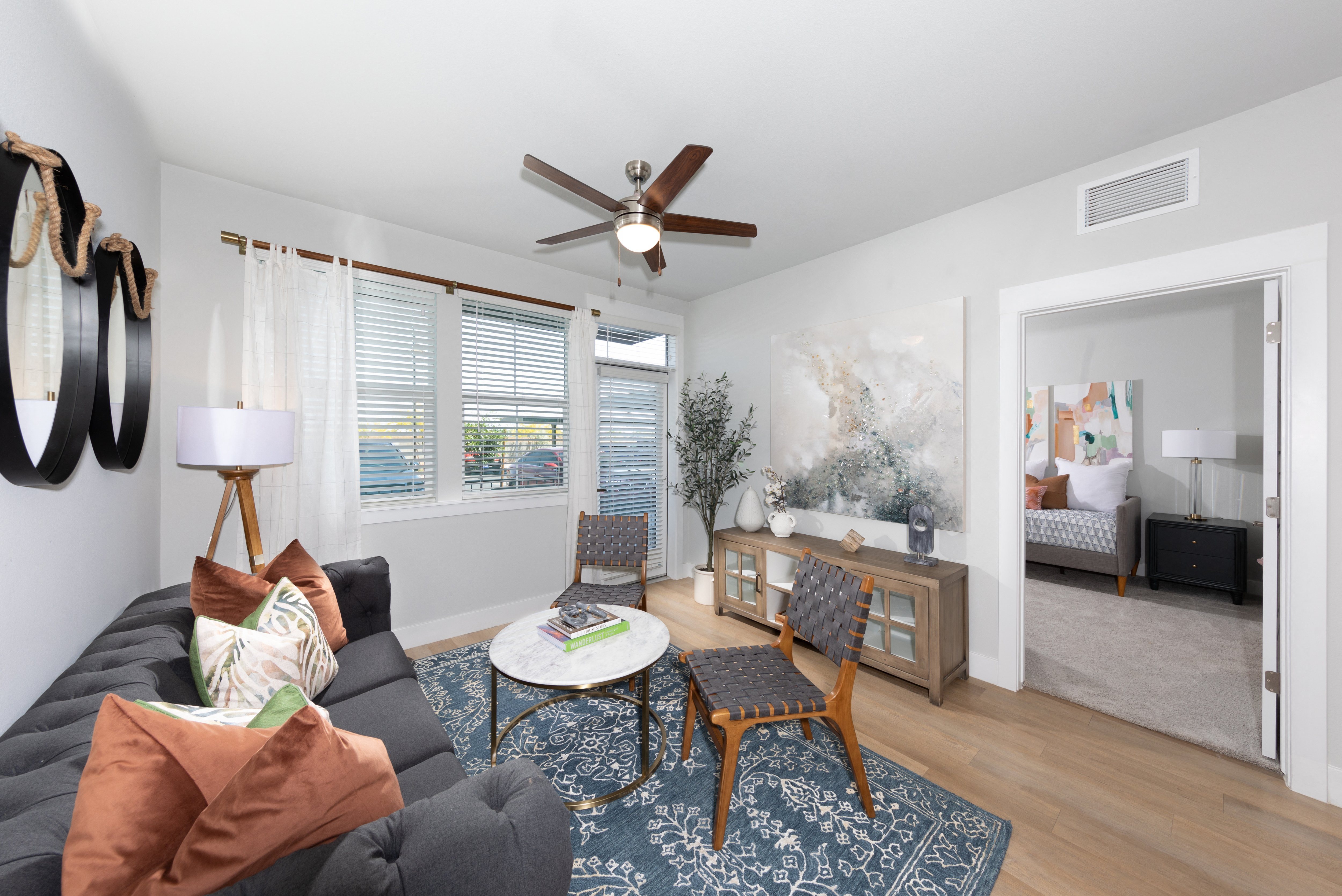 a living room with a ceiling fan and door that leads to a patio at a senior apartment community