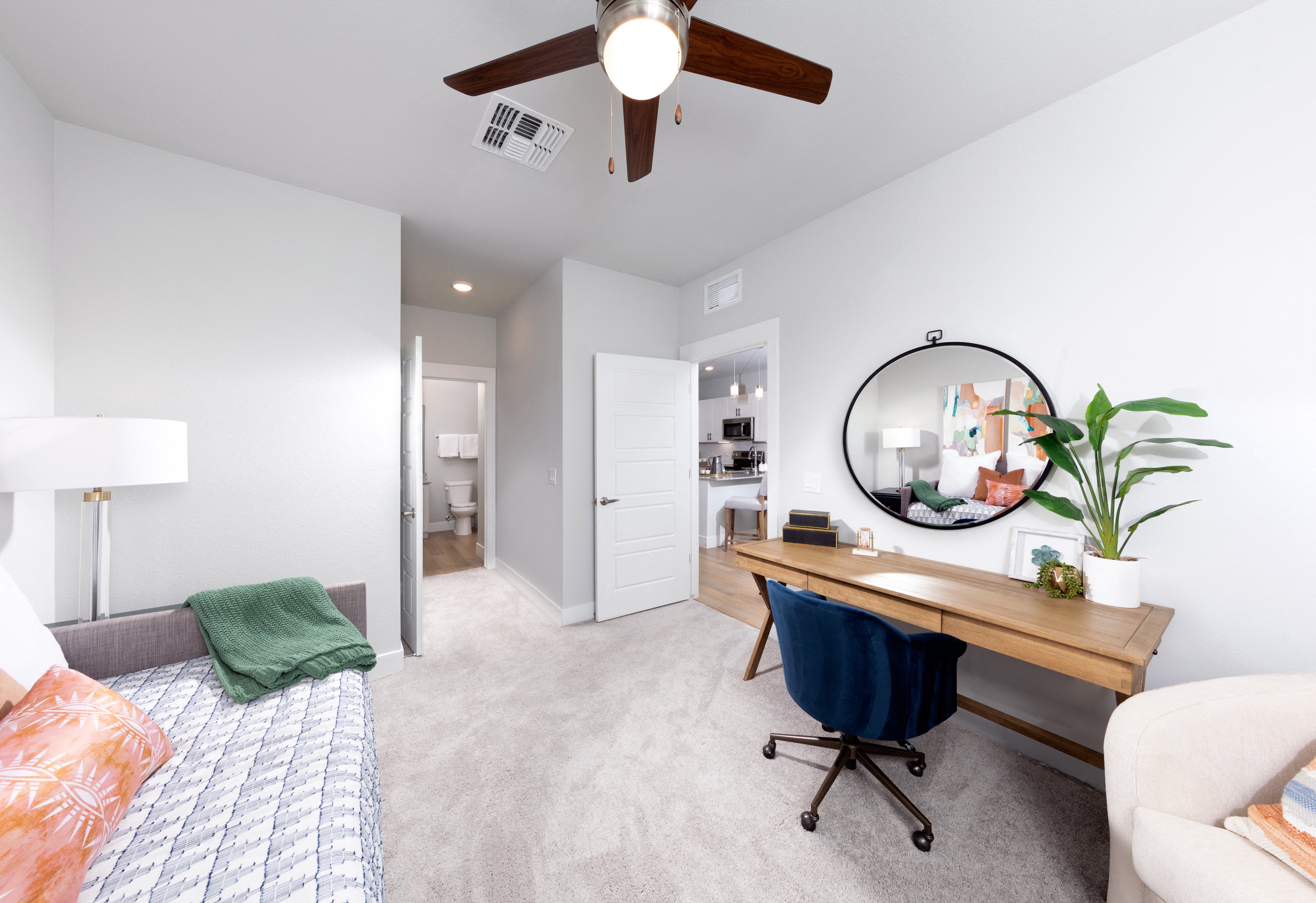 a bedroom with a daybed, desk, and ceiling fan at a senior apartment community