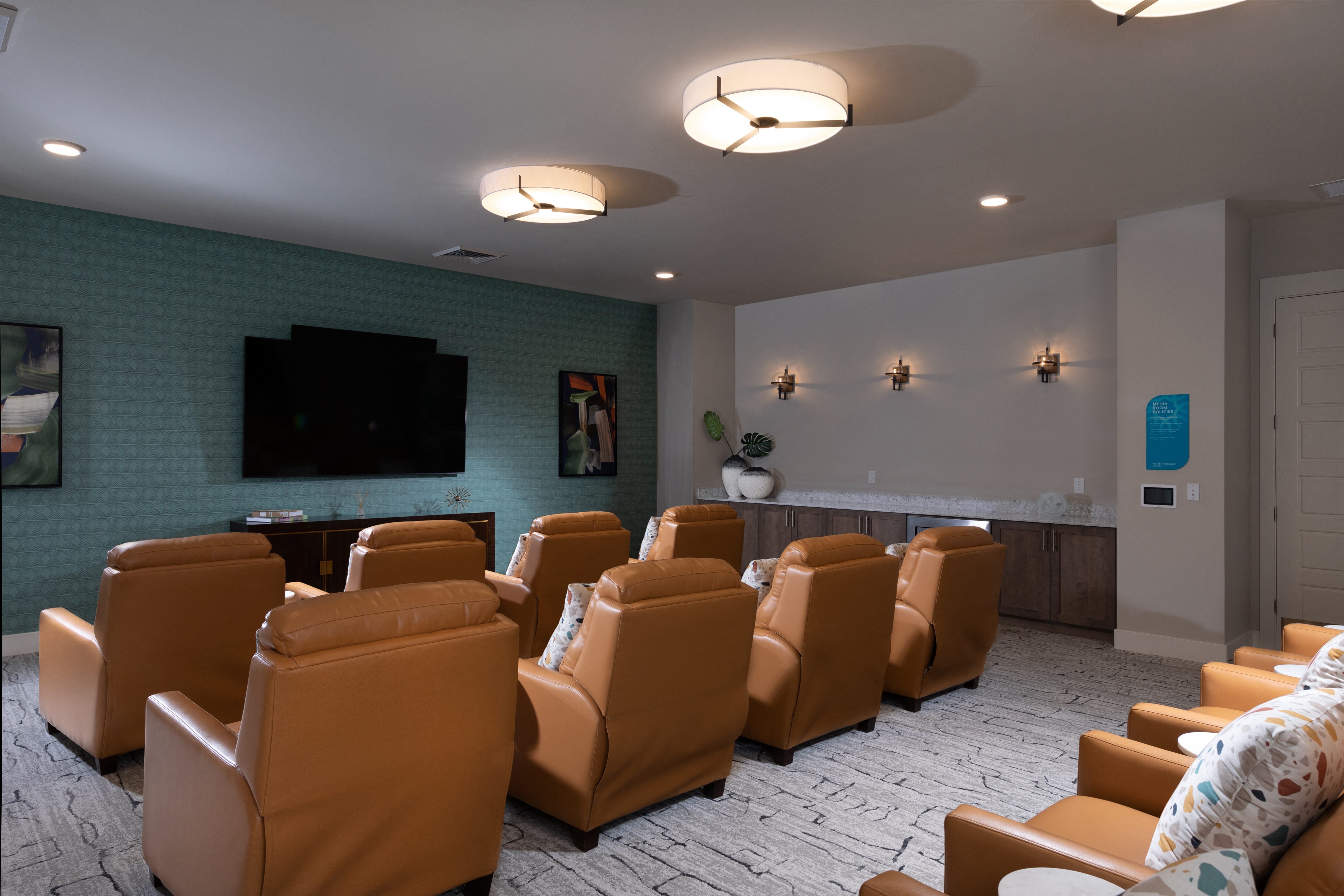 a media room with leather chairs and a large television at a senior apartment community