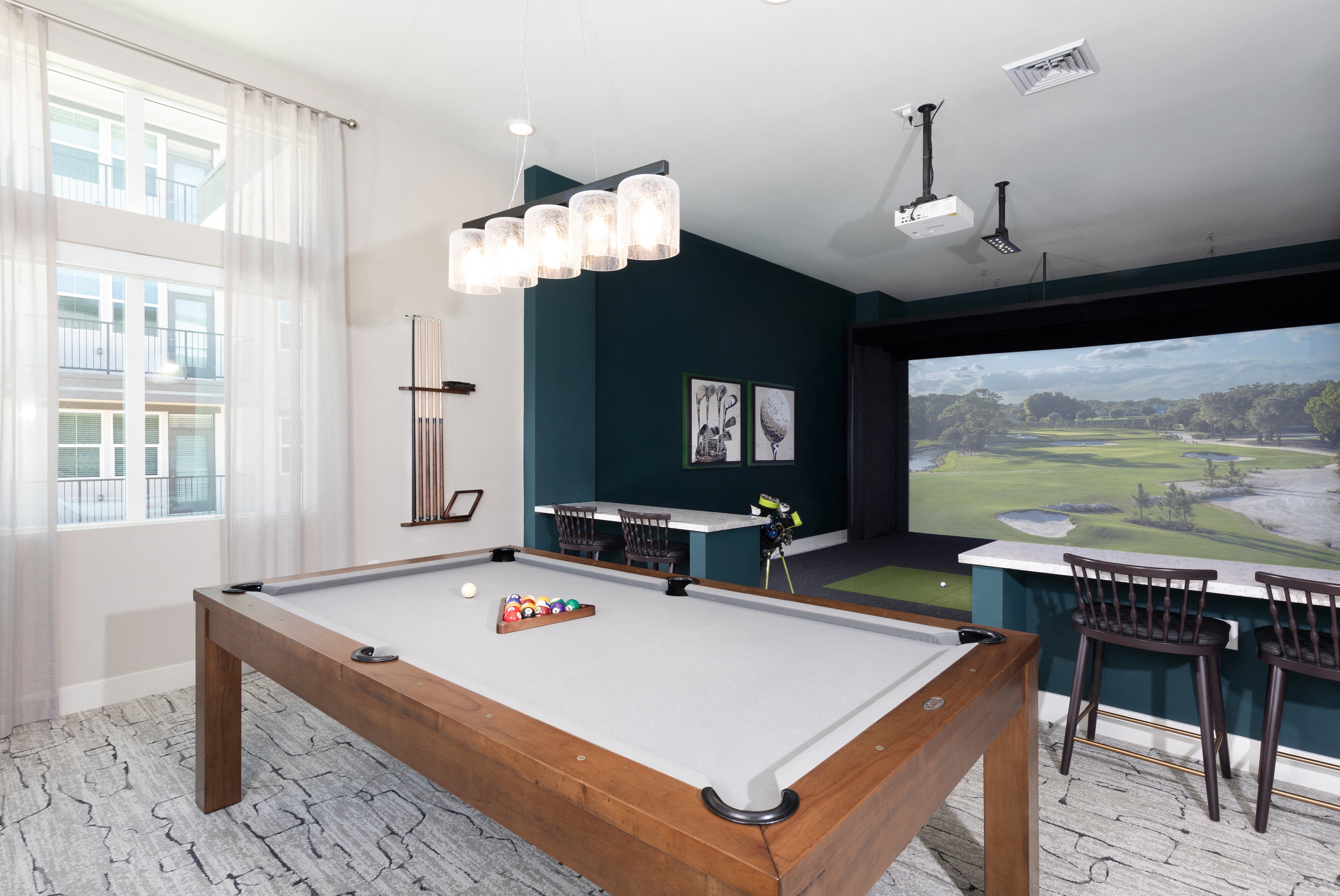 a game room with a gold simulator and pool table at a senior apartment community