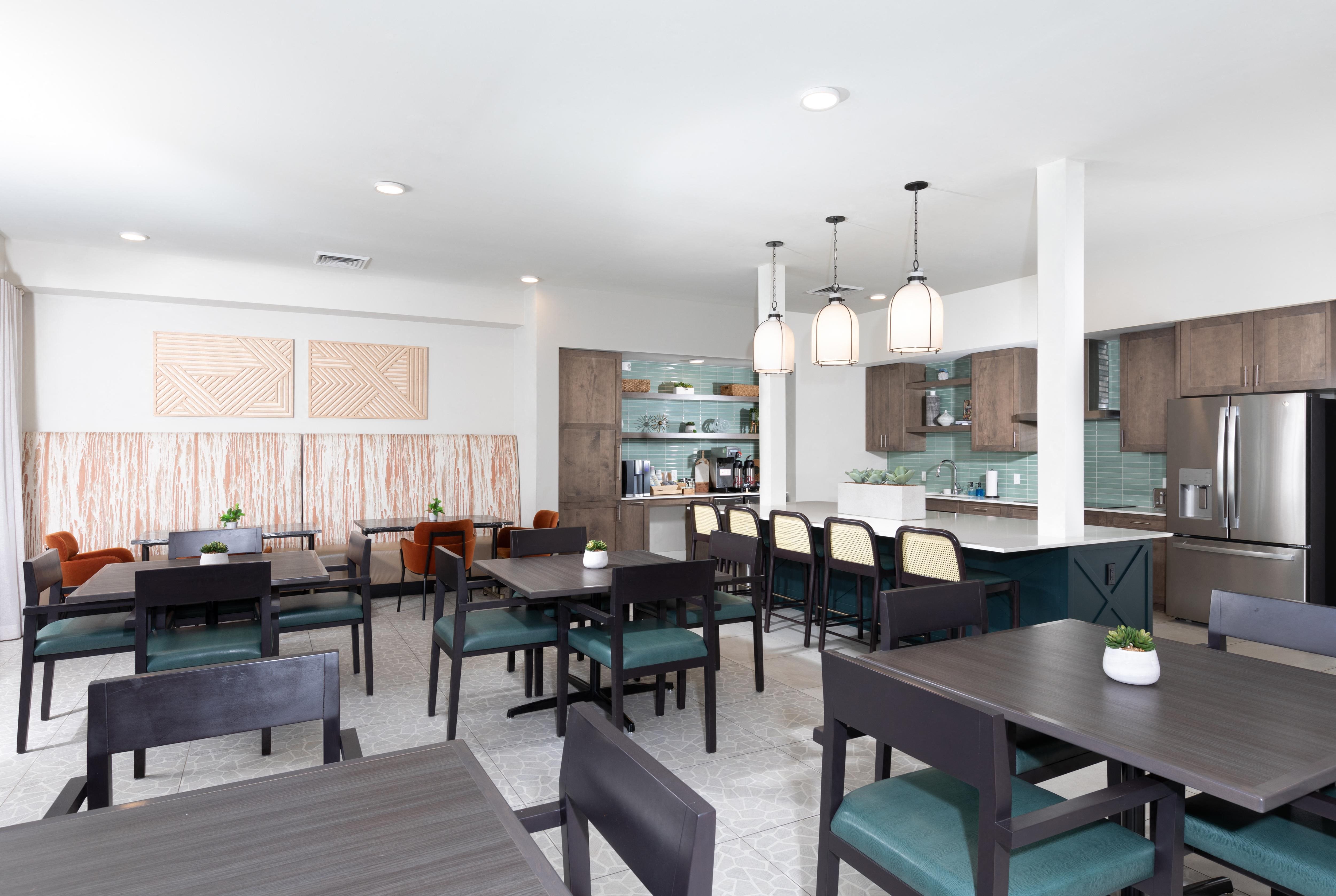 a communal clubhouse dining room opening up to a kitchen at a senior apartment community