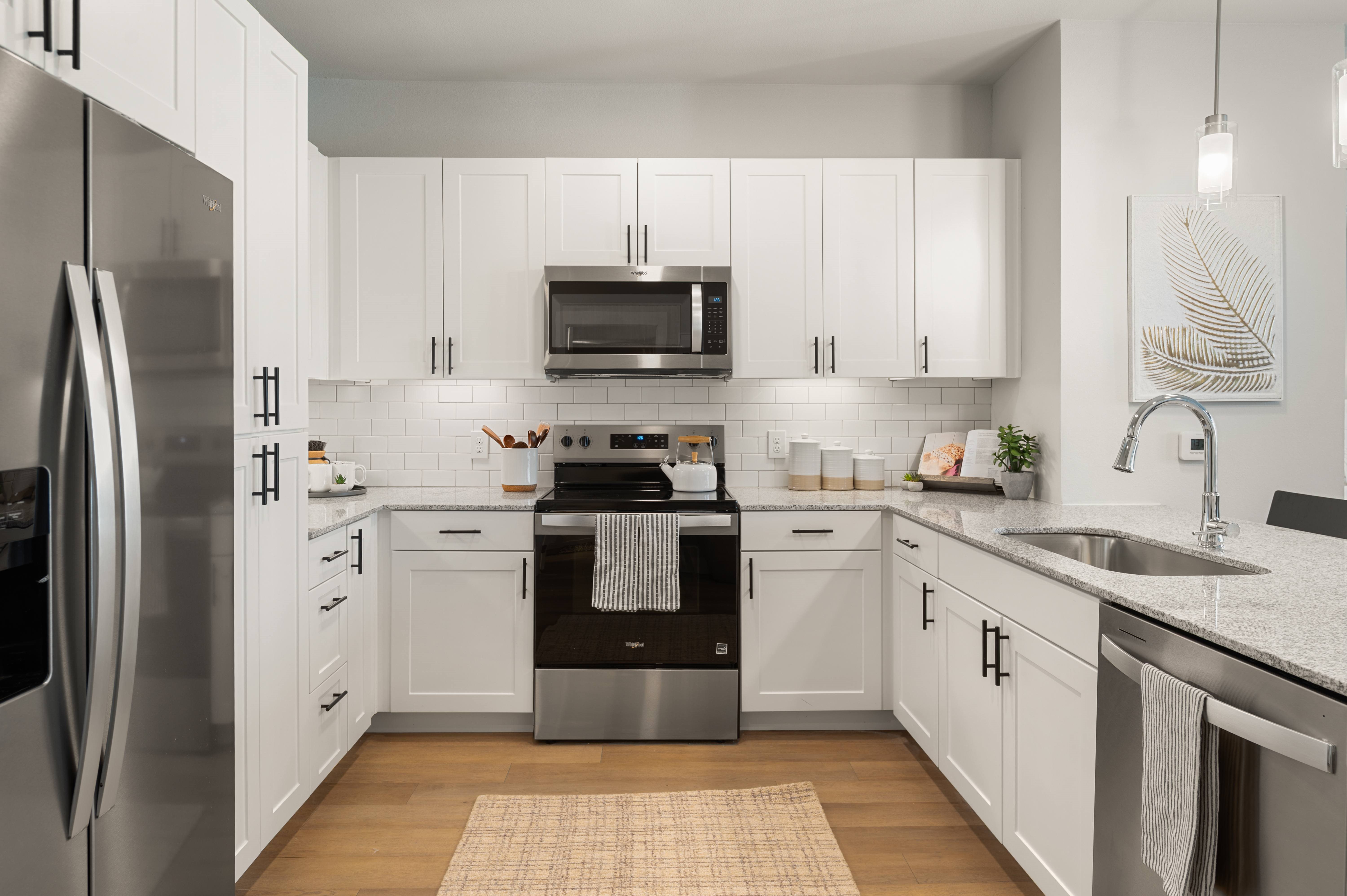 A modern kitchen with white cabinets and stainless steel appliances.