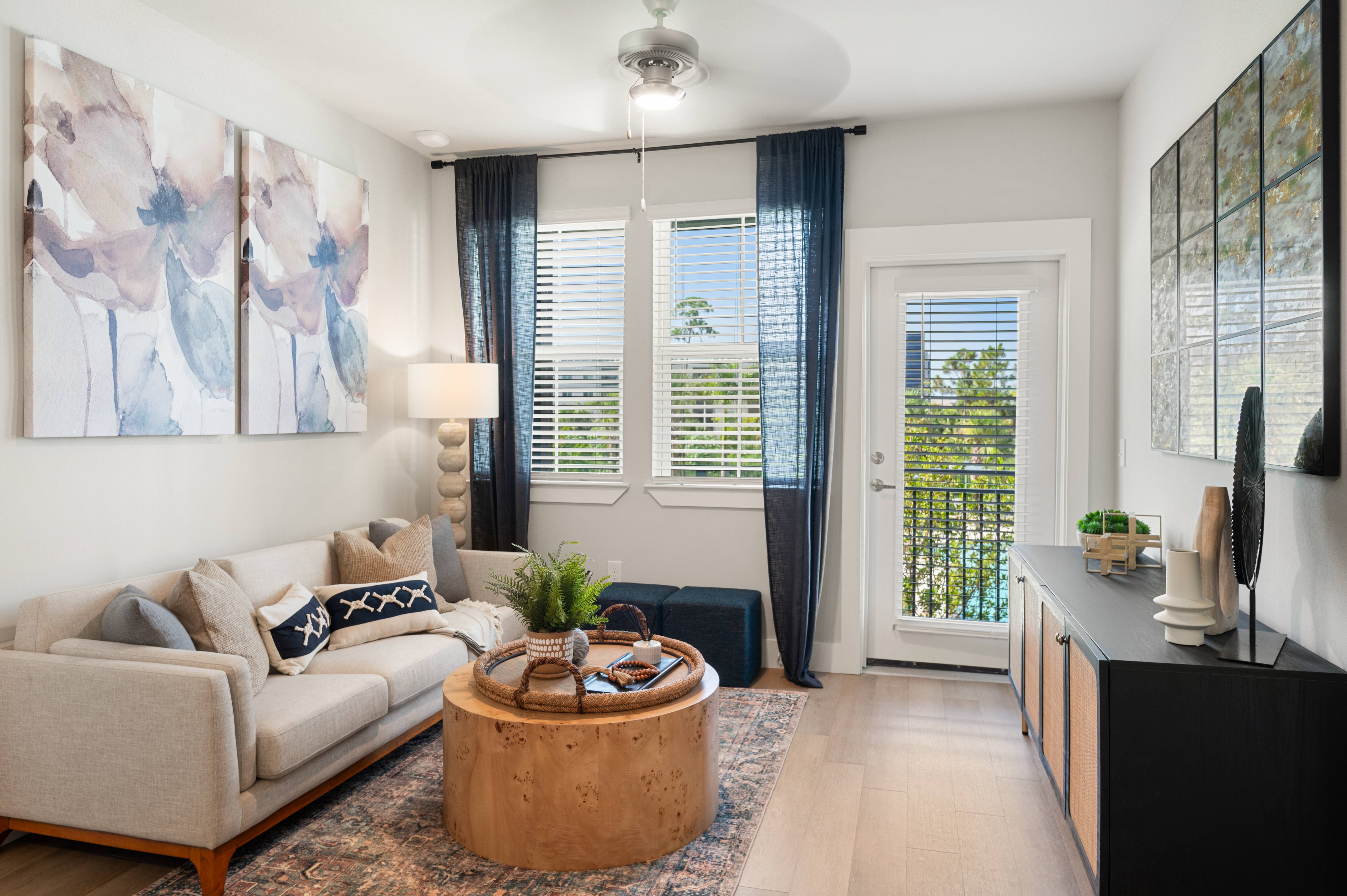 A living room with a beige couch, a wooden coffee table, and a painting on the wall.