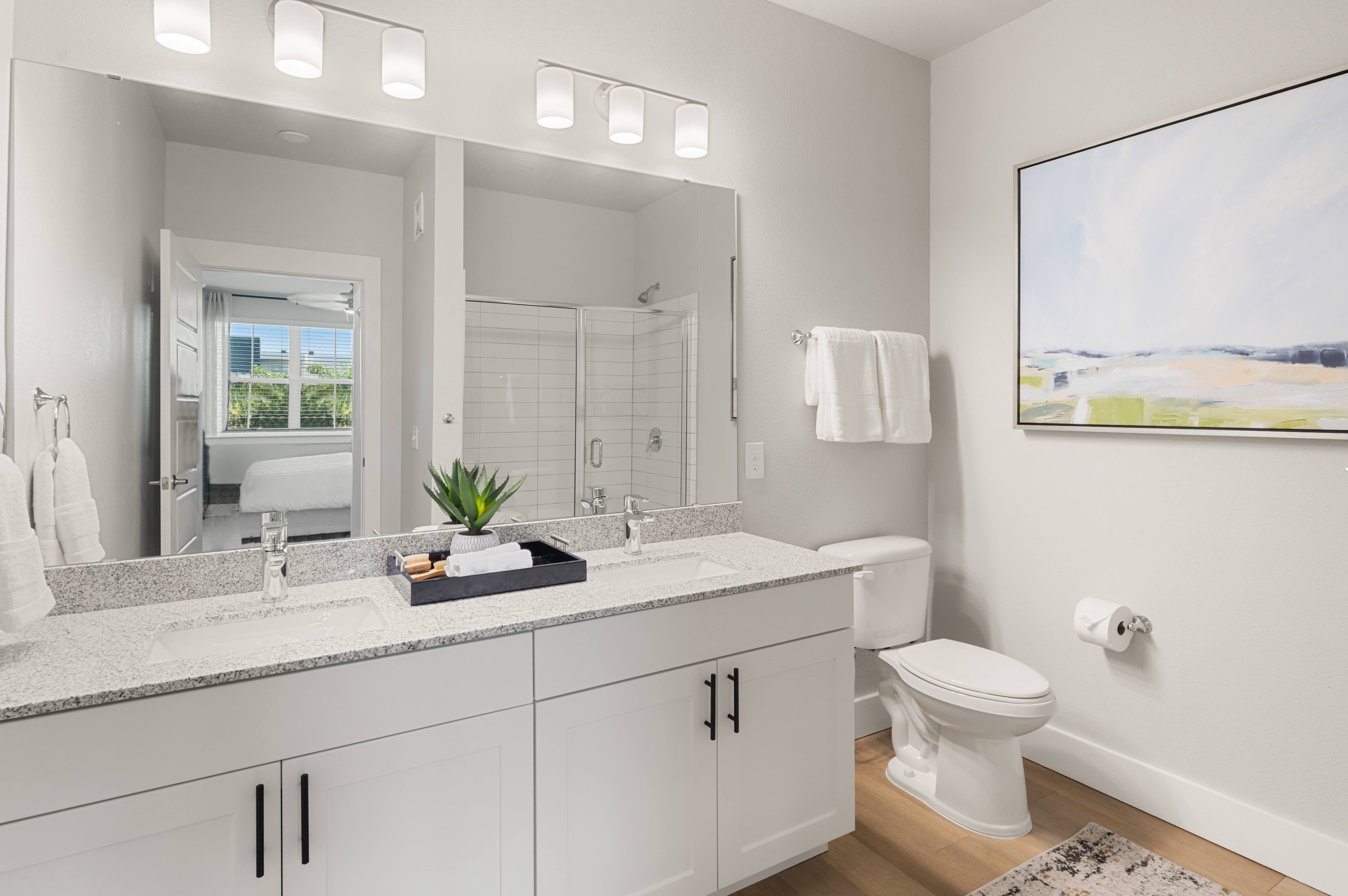 A white bathroom with a large mirror and a window.