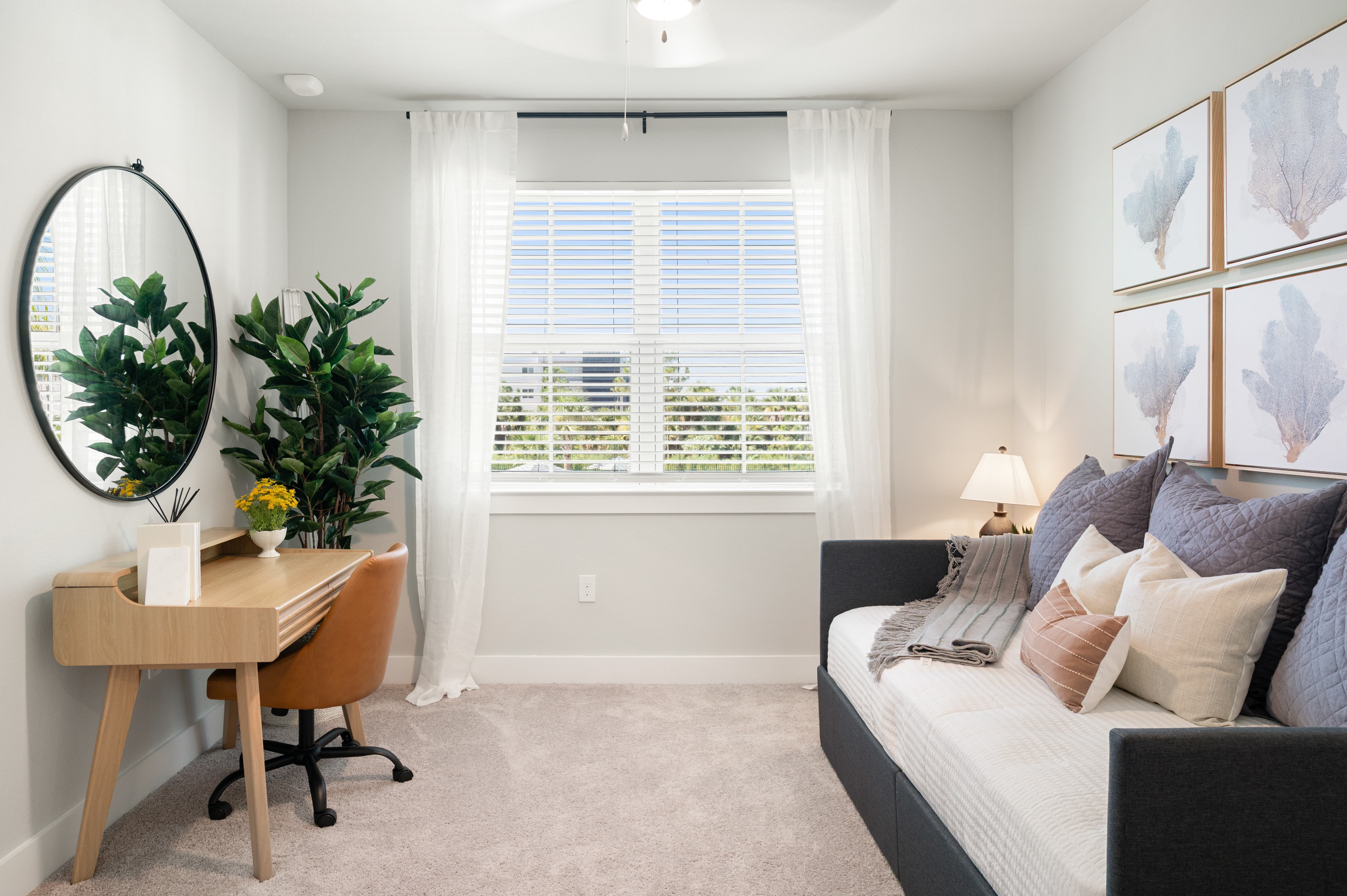A well-lit bedroom with a bed, desk, and window.