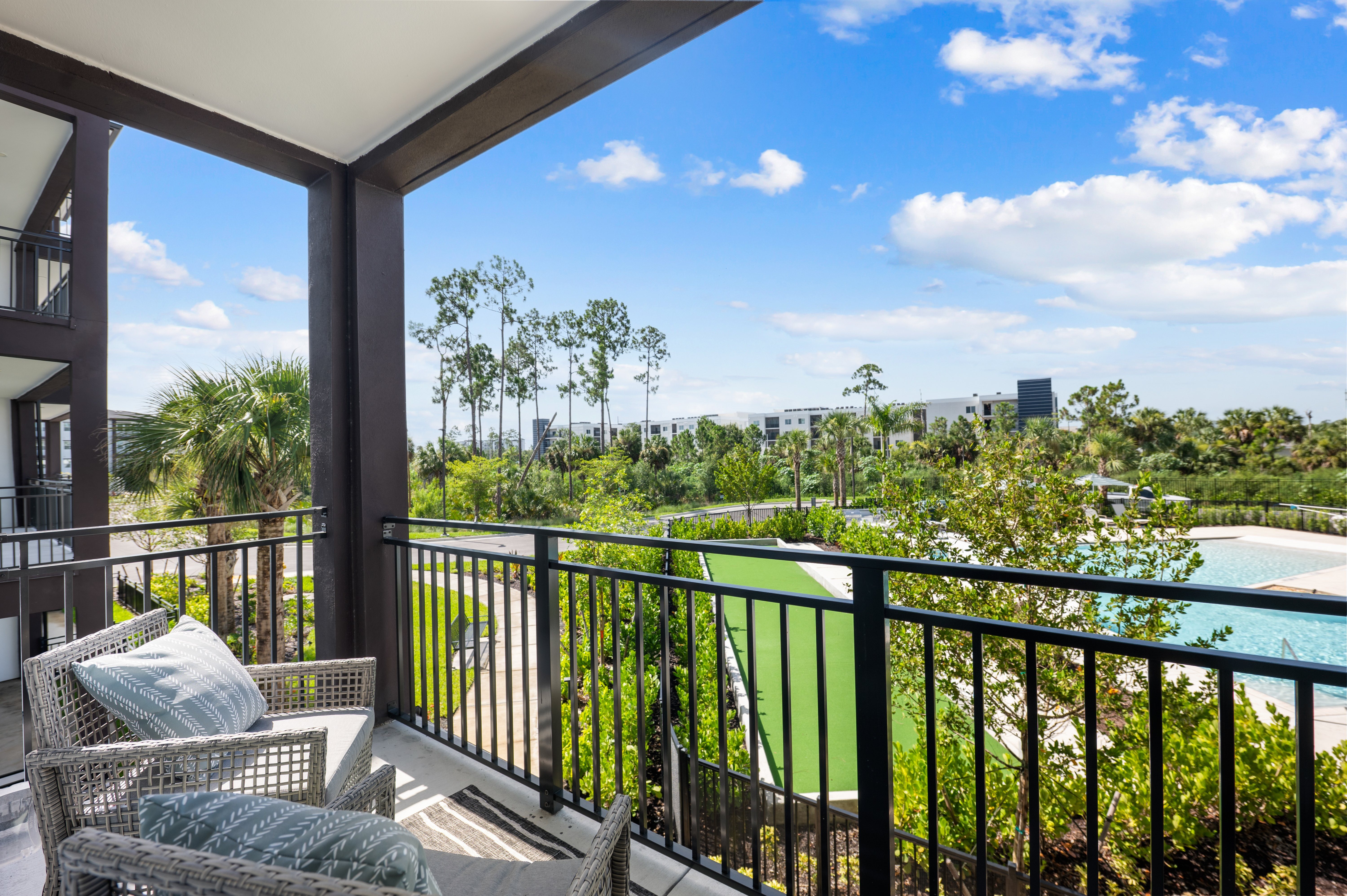 A balcony with a chair and a view of a pool and trees.
