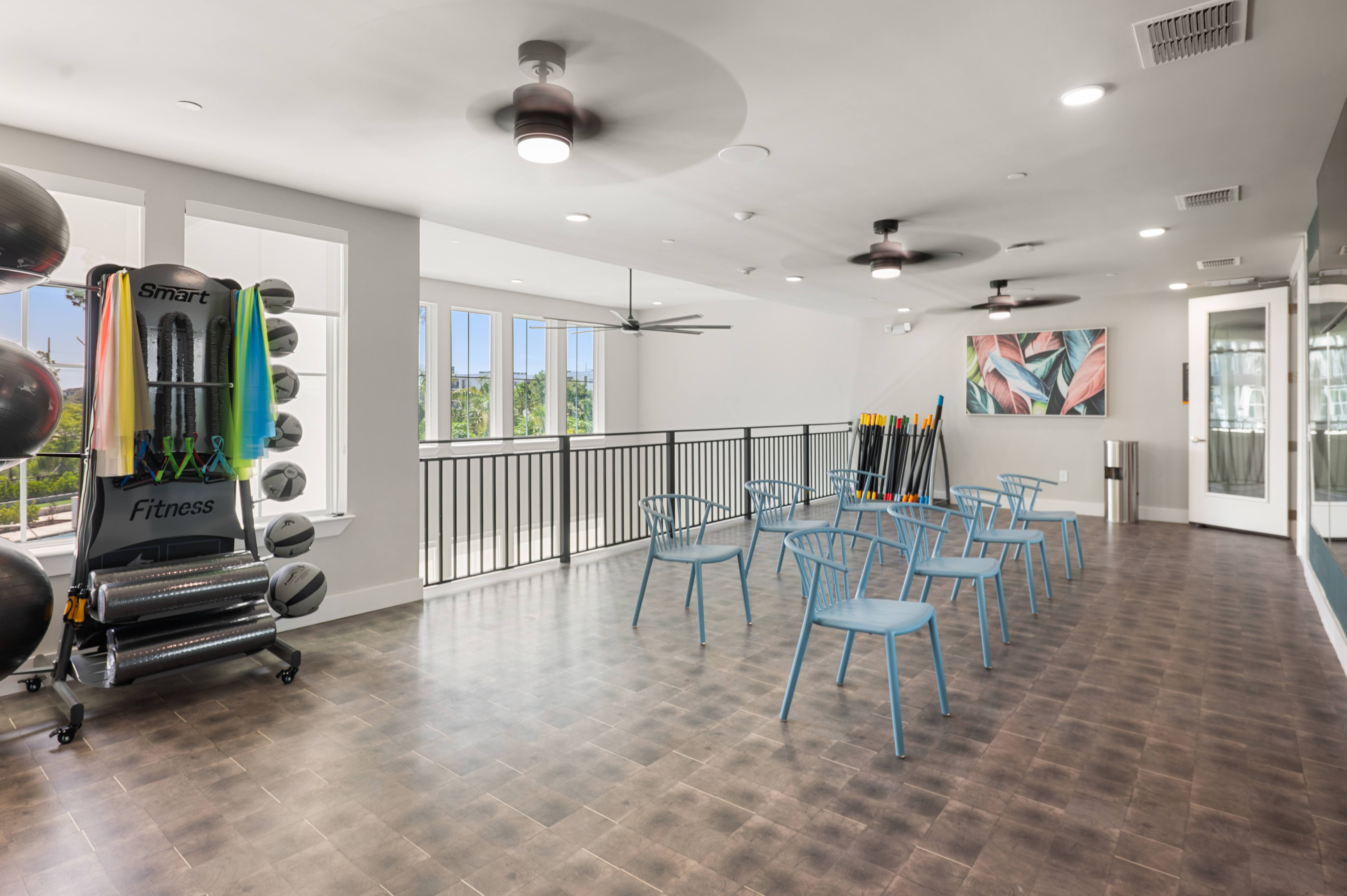 A gym with a row of blue chairs and a treadmill.