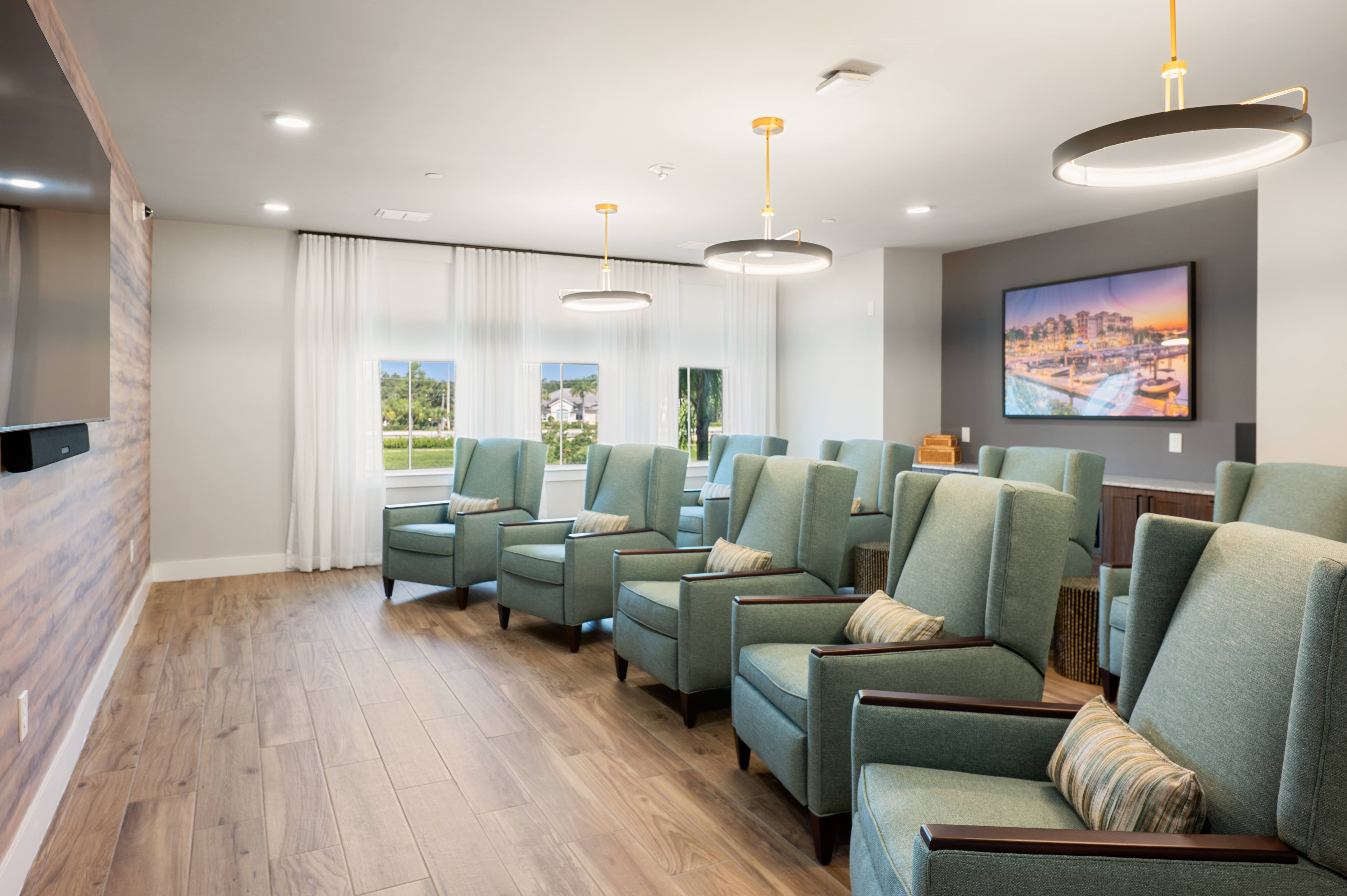A row of green chairs are lined up in a waiting area.