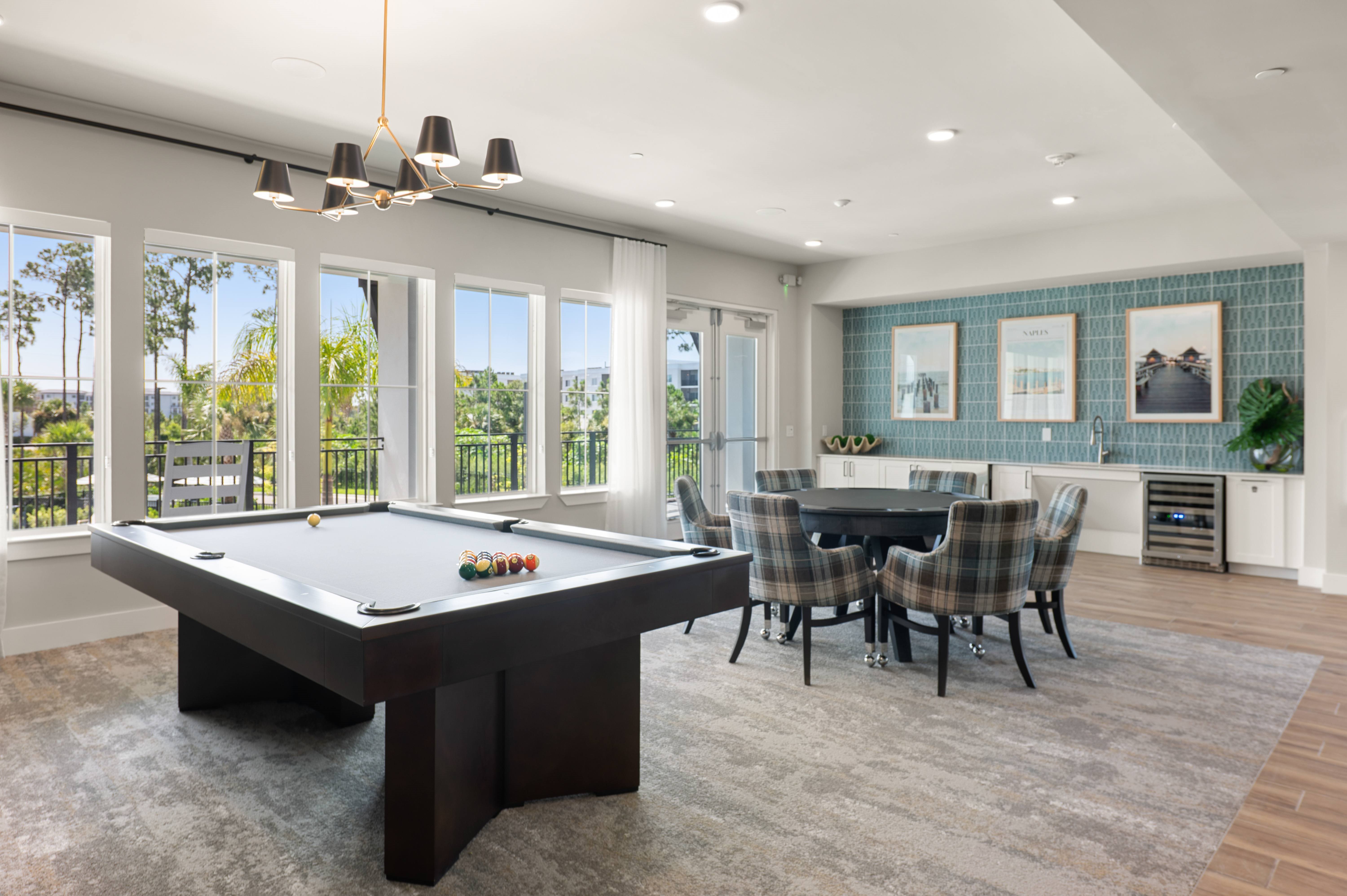 A pool table is in the middle of a room with a dining table and chairs.
