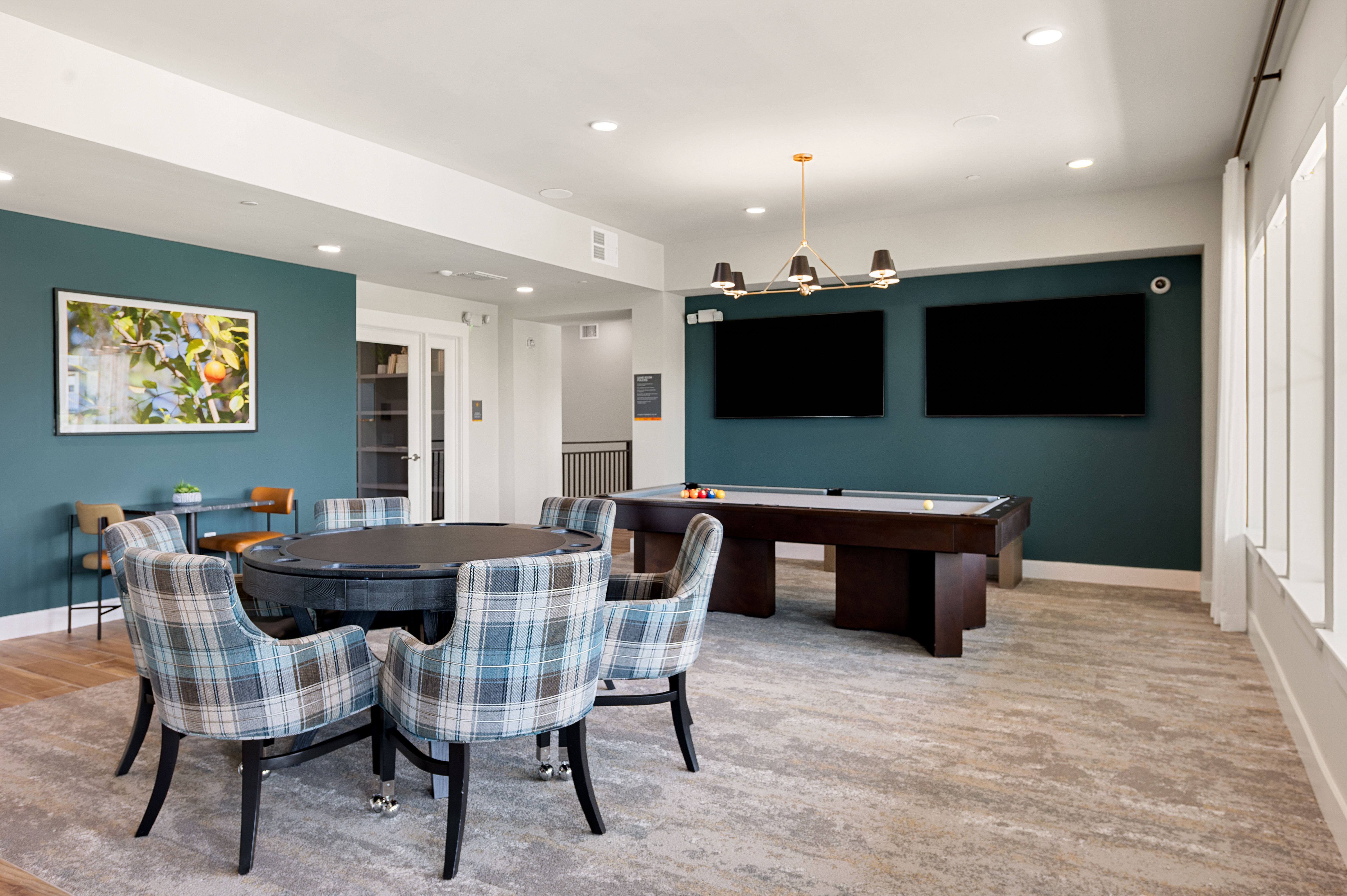 A room with a pool table and chairs.
