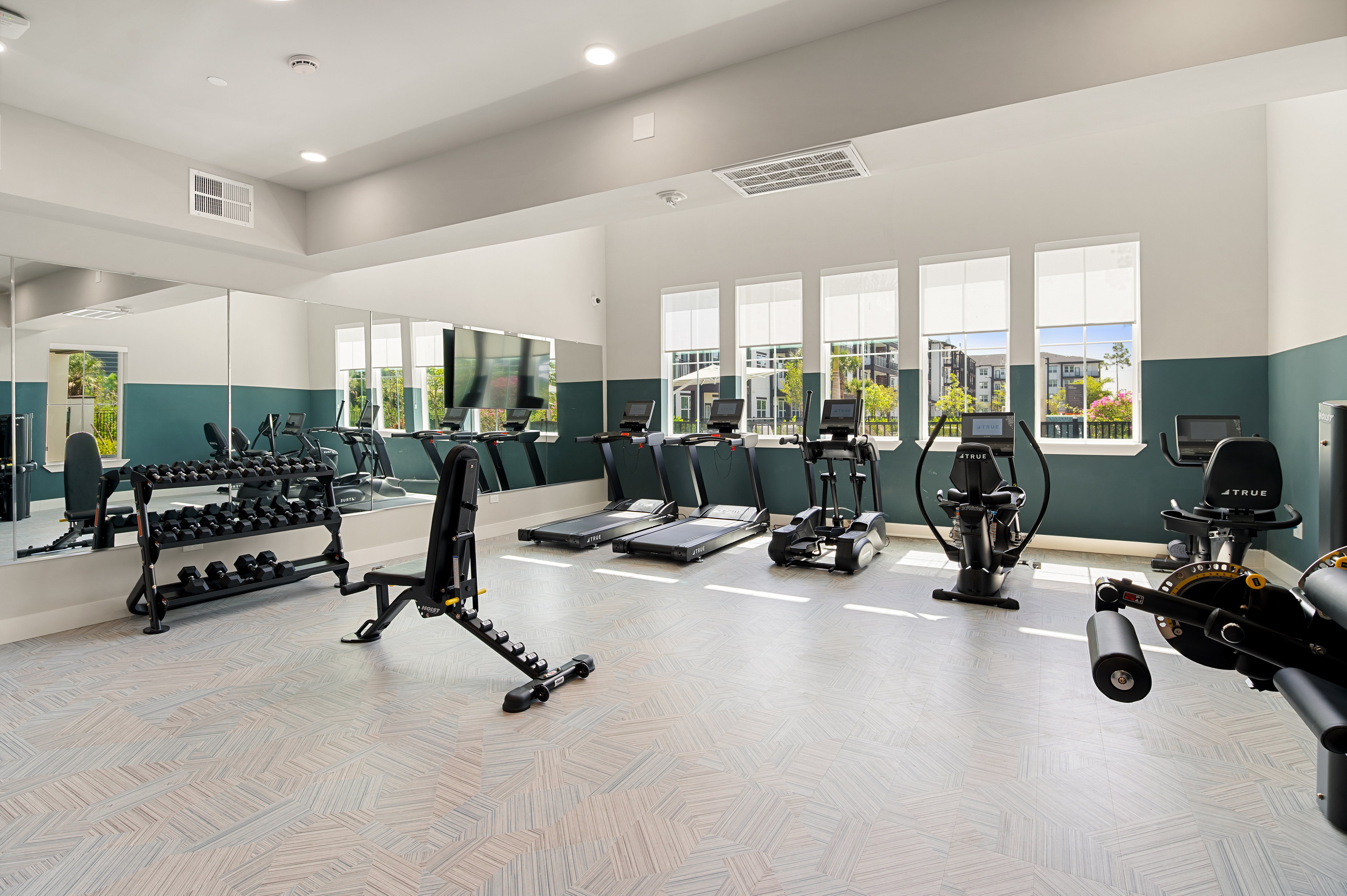 A gym with a variety of equipment including treadmills, stationary bikes, and weight machines.