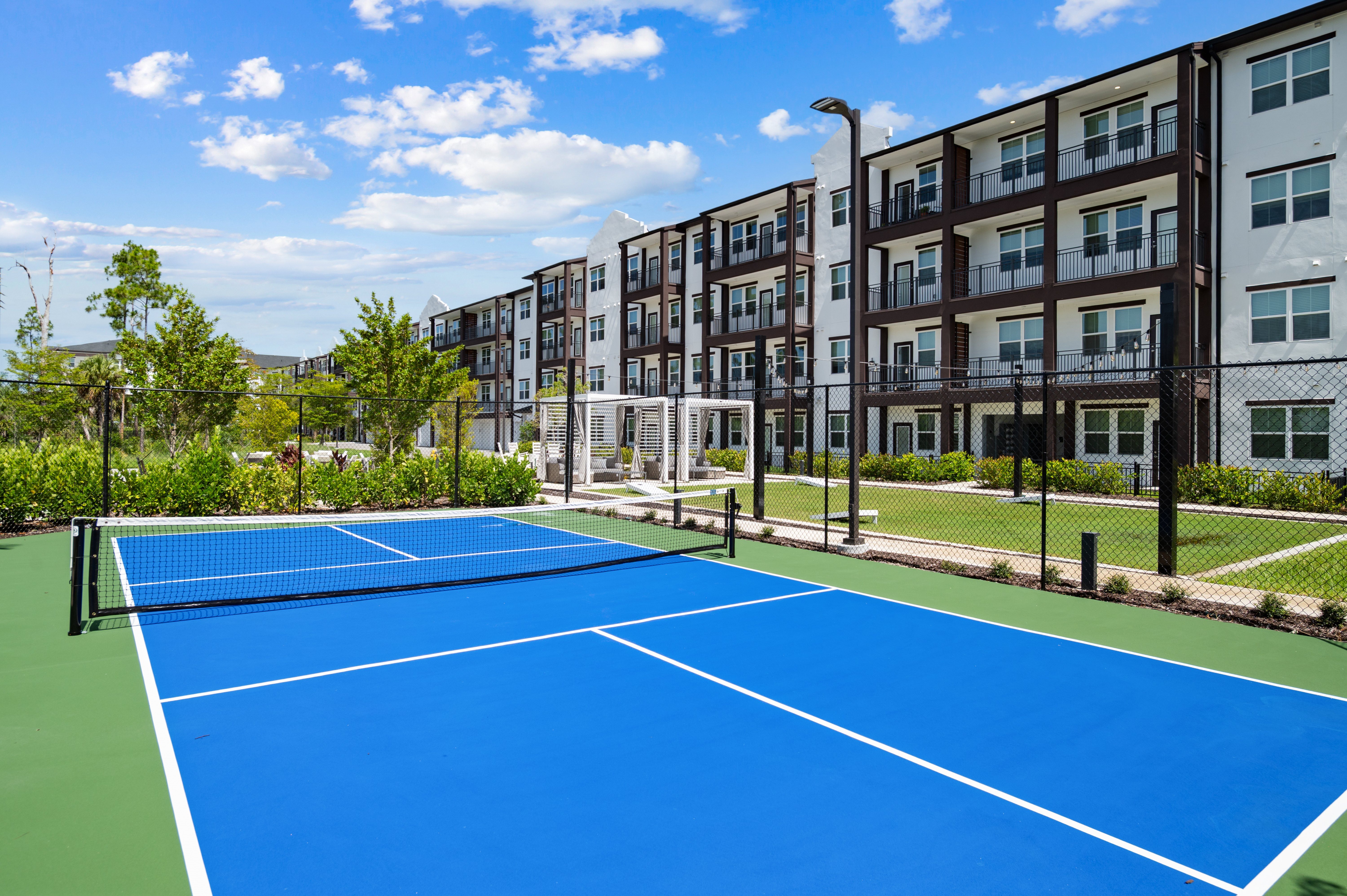 A tennis court is surrounded by apartment buildings.