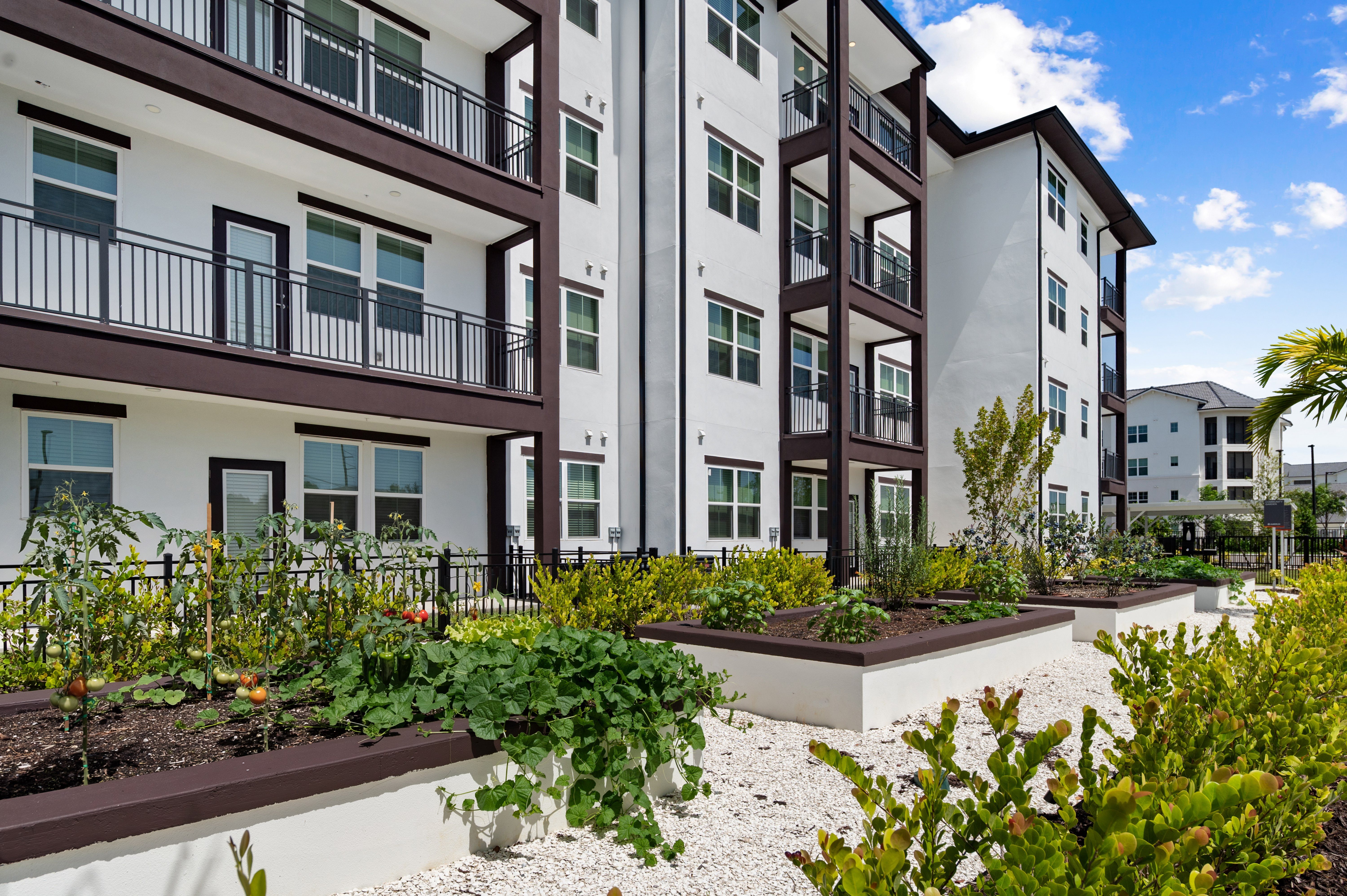 A modern apartment complex with a well-maintained garden in front.
