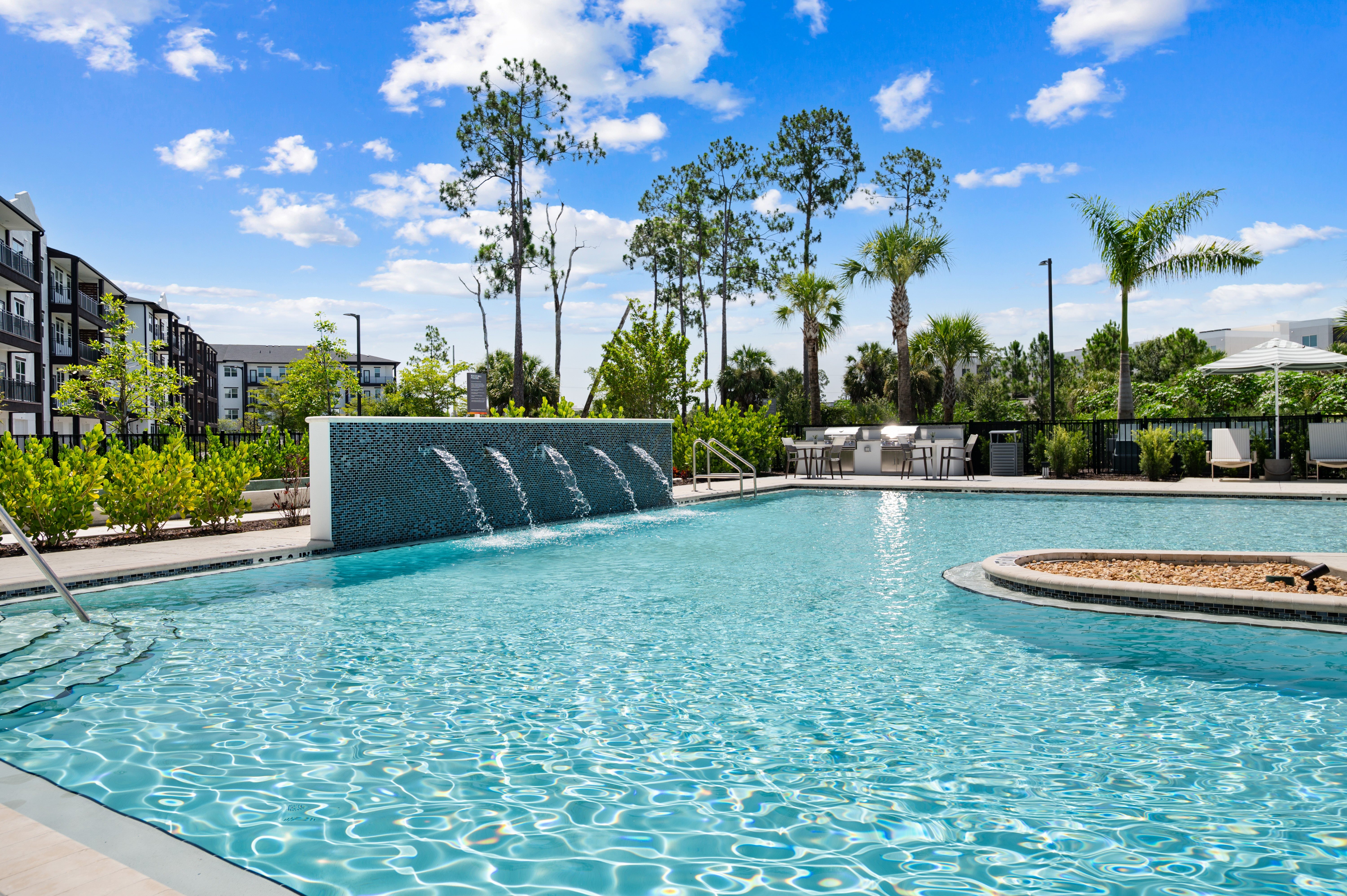A large swimming pool with a waterfall feature in the middle.
