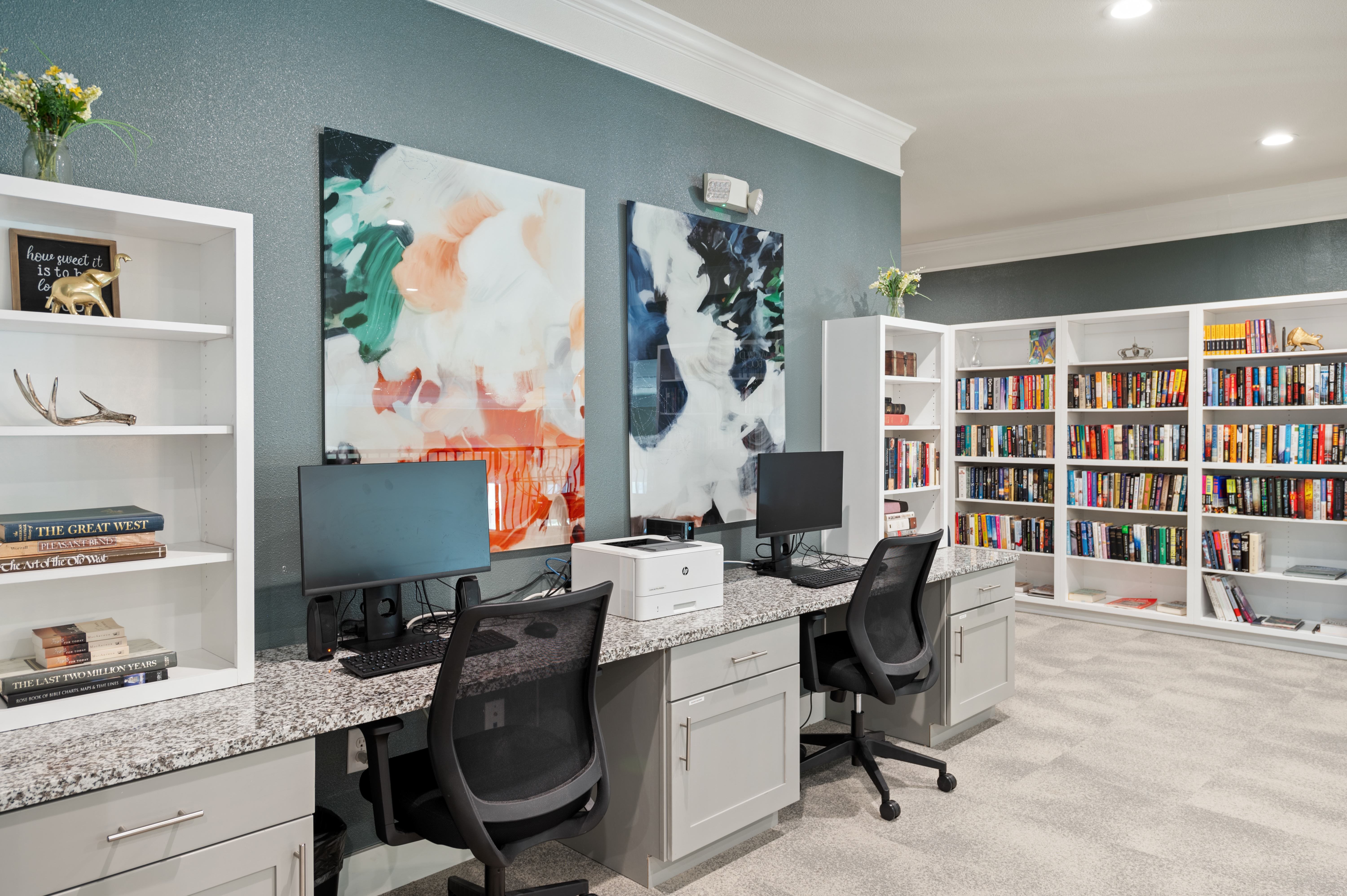 A home office with a desk, chairs, and a bookshelf.