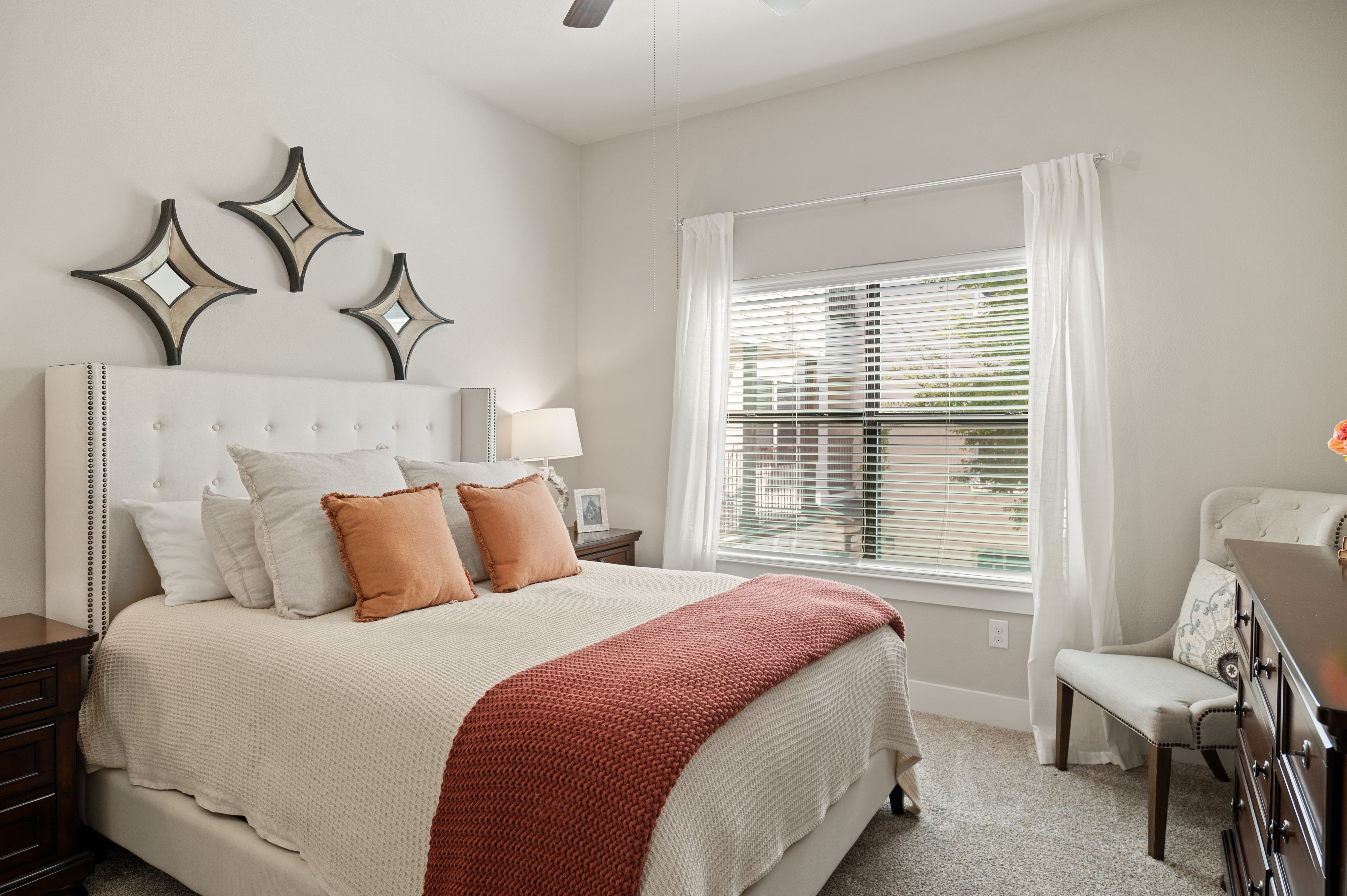 A bedroom with a large bed and a window with blinds.