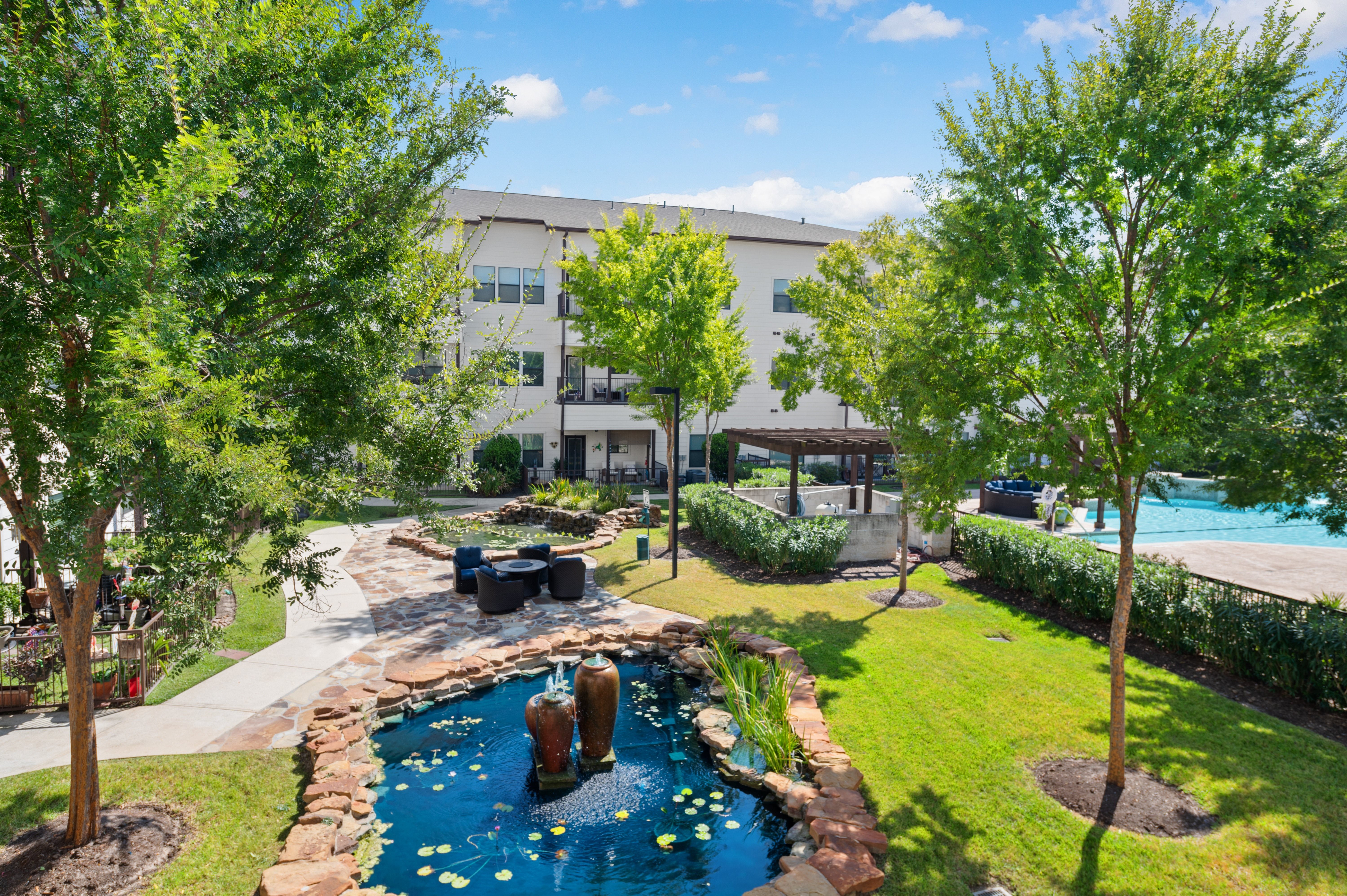 A pool with a waterfall and a small pond in the middle of a grassy area.