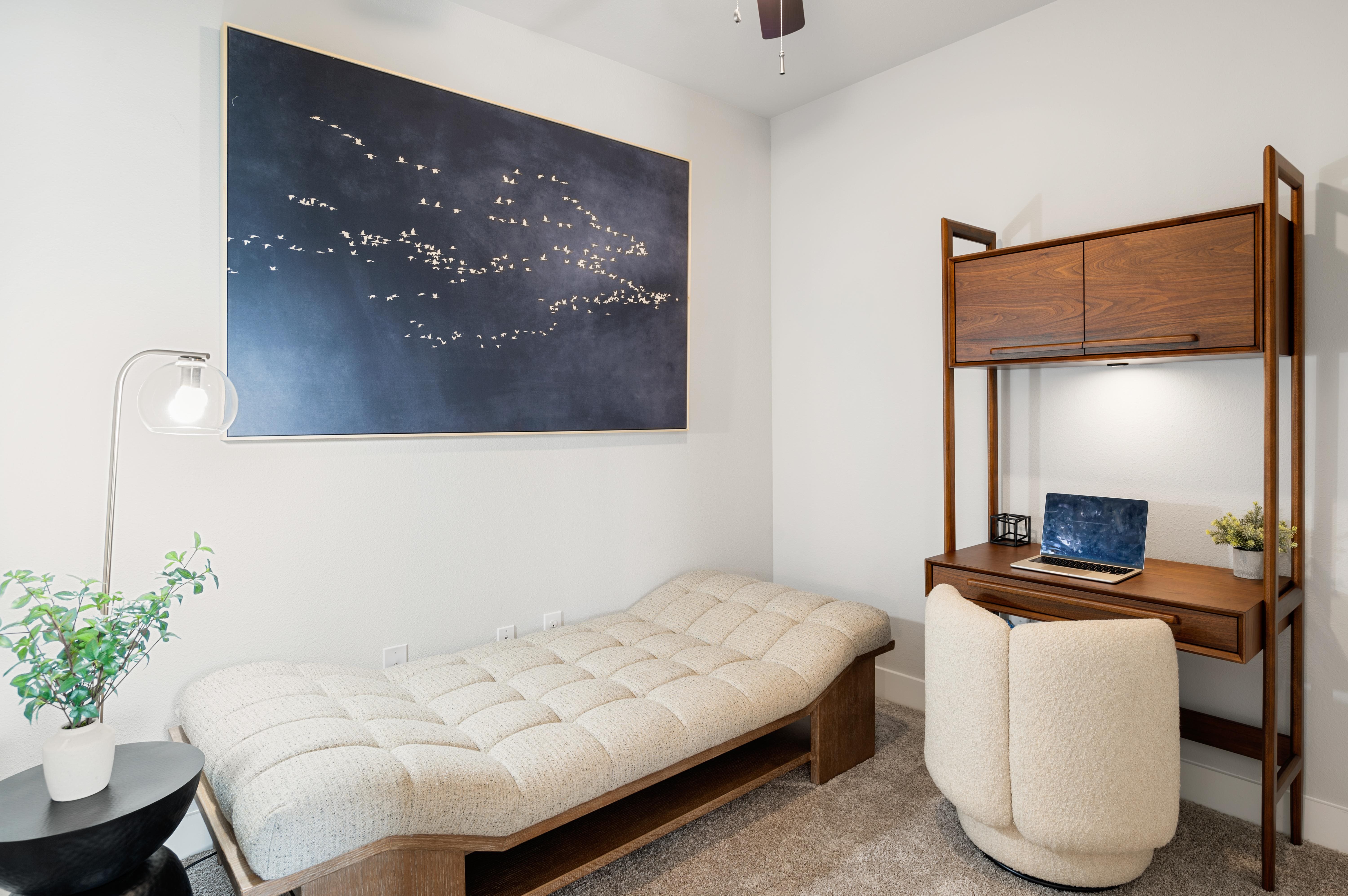 A bedroom with a bed, desk, and a painting of a night sky.