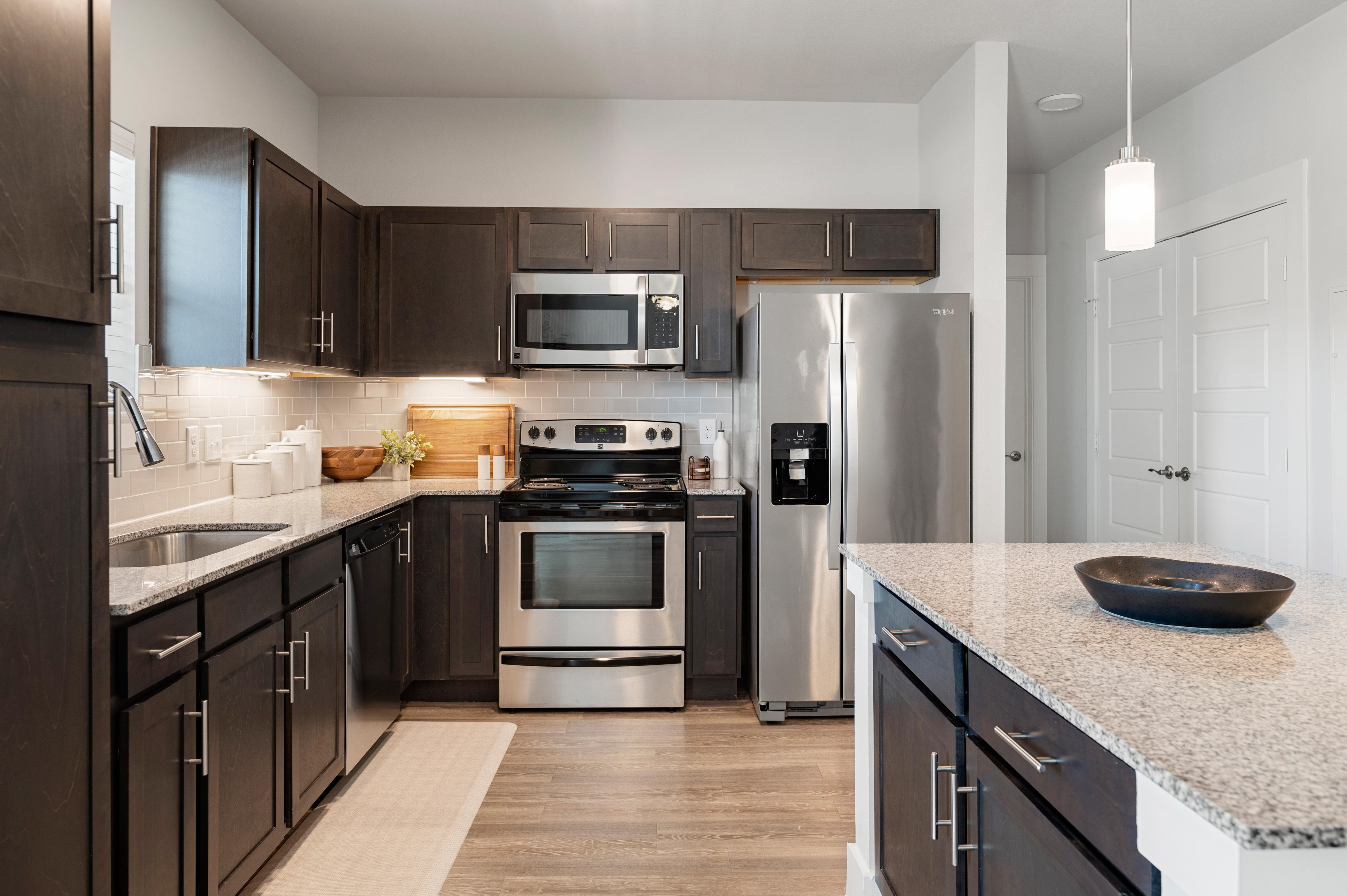 A modern kitchen with dark brown cabinets and stainless steel appliances.